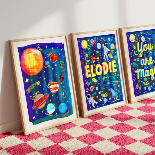 Three framed space-themed artworks on a pink and white checkered rug.