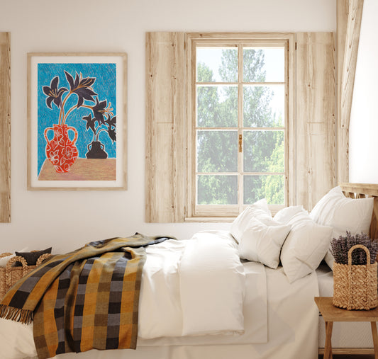 Cozy bedroom with a bed, plaid blanket, and Moody Floral Artwork on the wall.