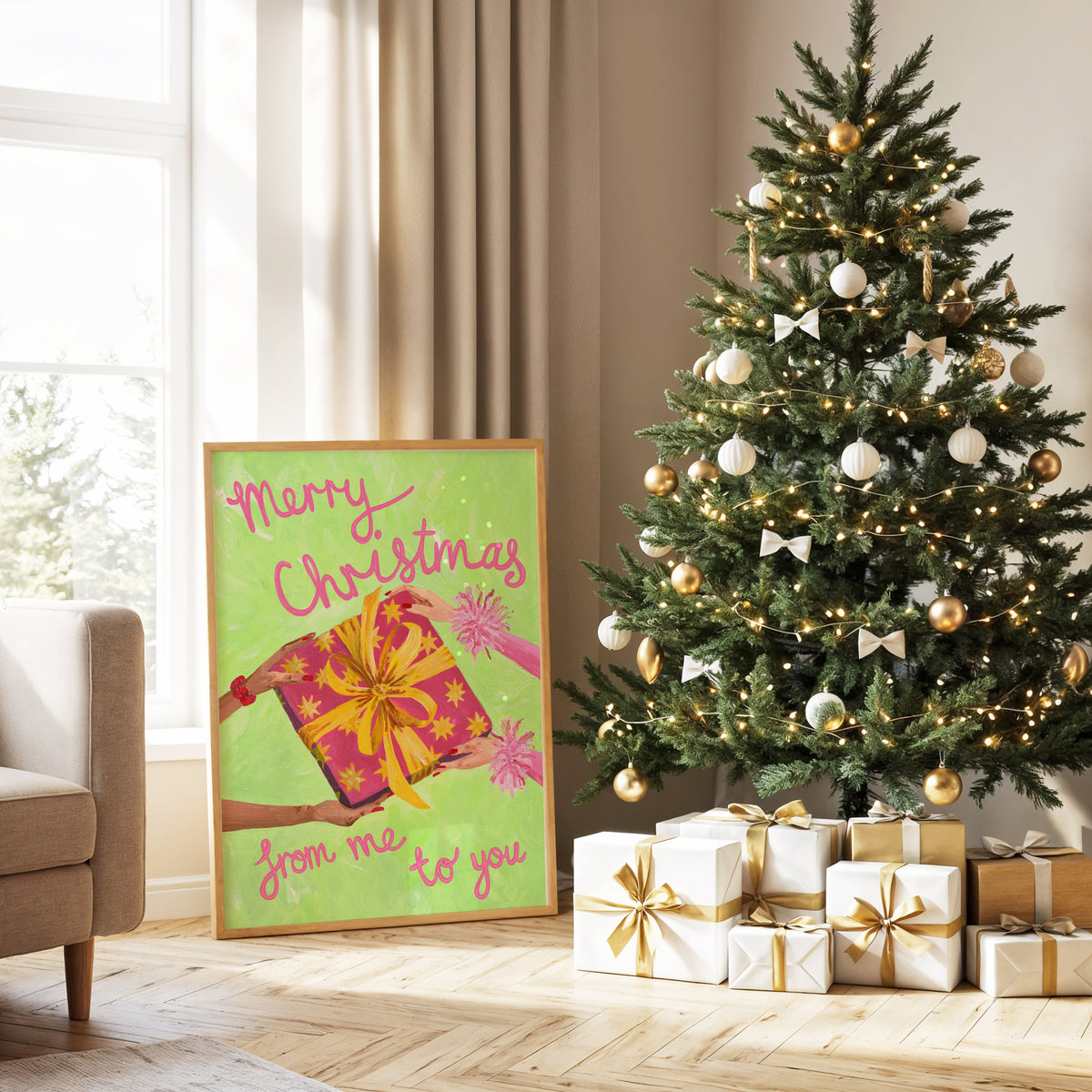 A framed Christmas art print with the text 'Merry Christmas from me to you' and an illustration of a pink and yellow gift box, leaning against a wall next to a decorated Christmas tree and wrapped presents in a bright living room.