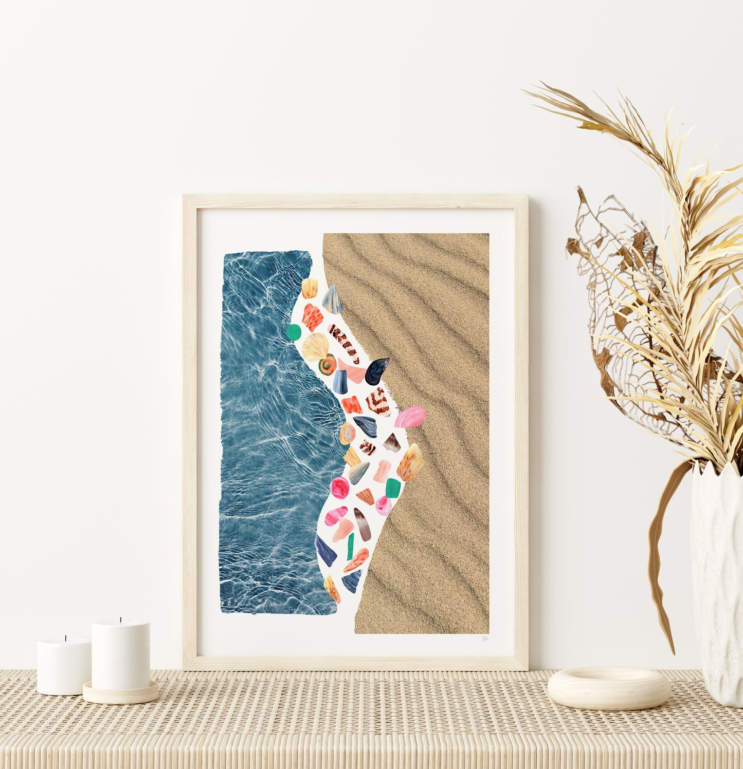 Framed artwork of a beach scene with ocean and sand on a wall.