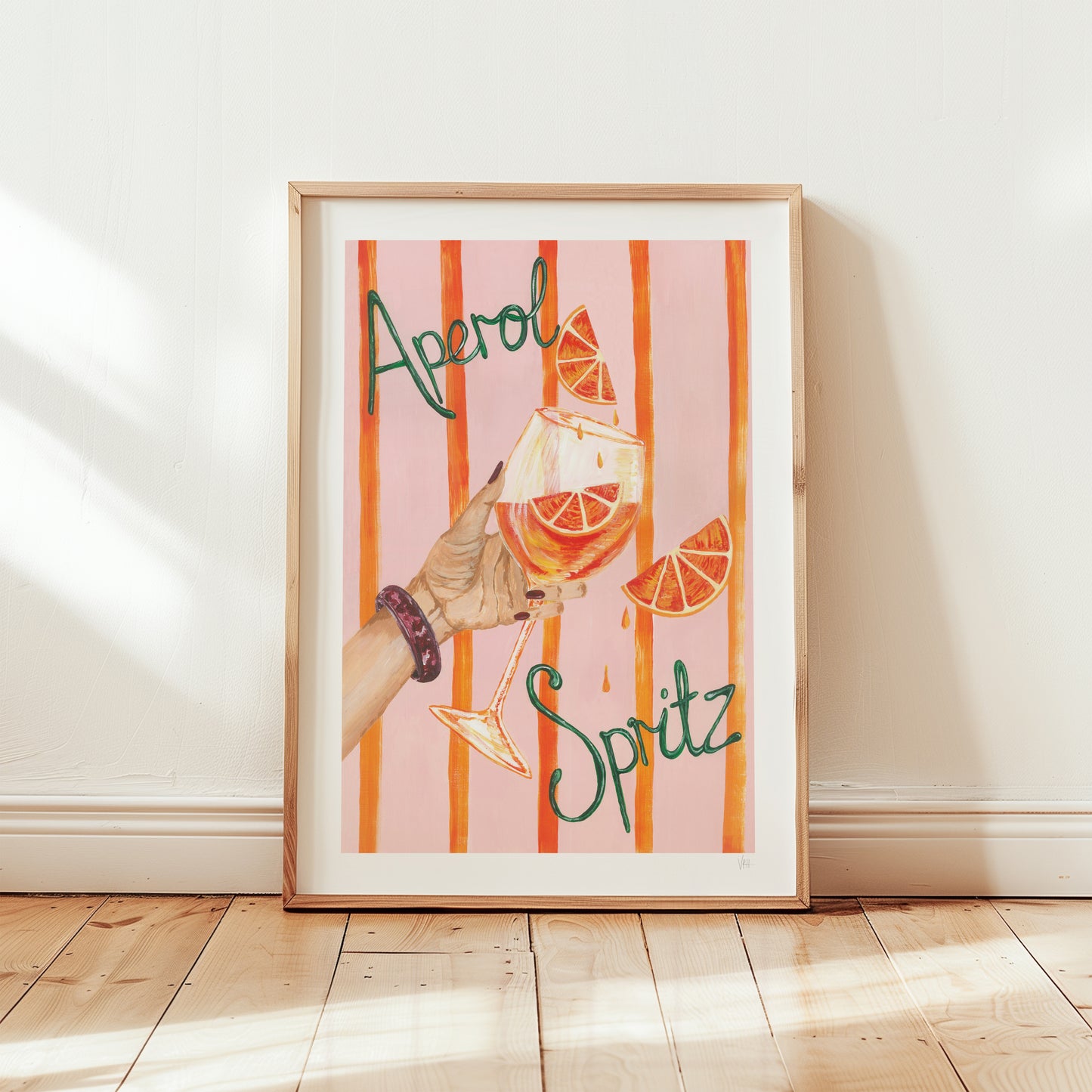 Framed artwork with a glass of Aperol Spritz and orange slices on a striped background.