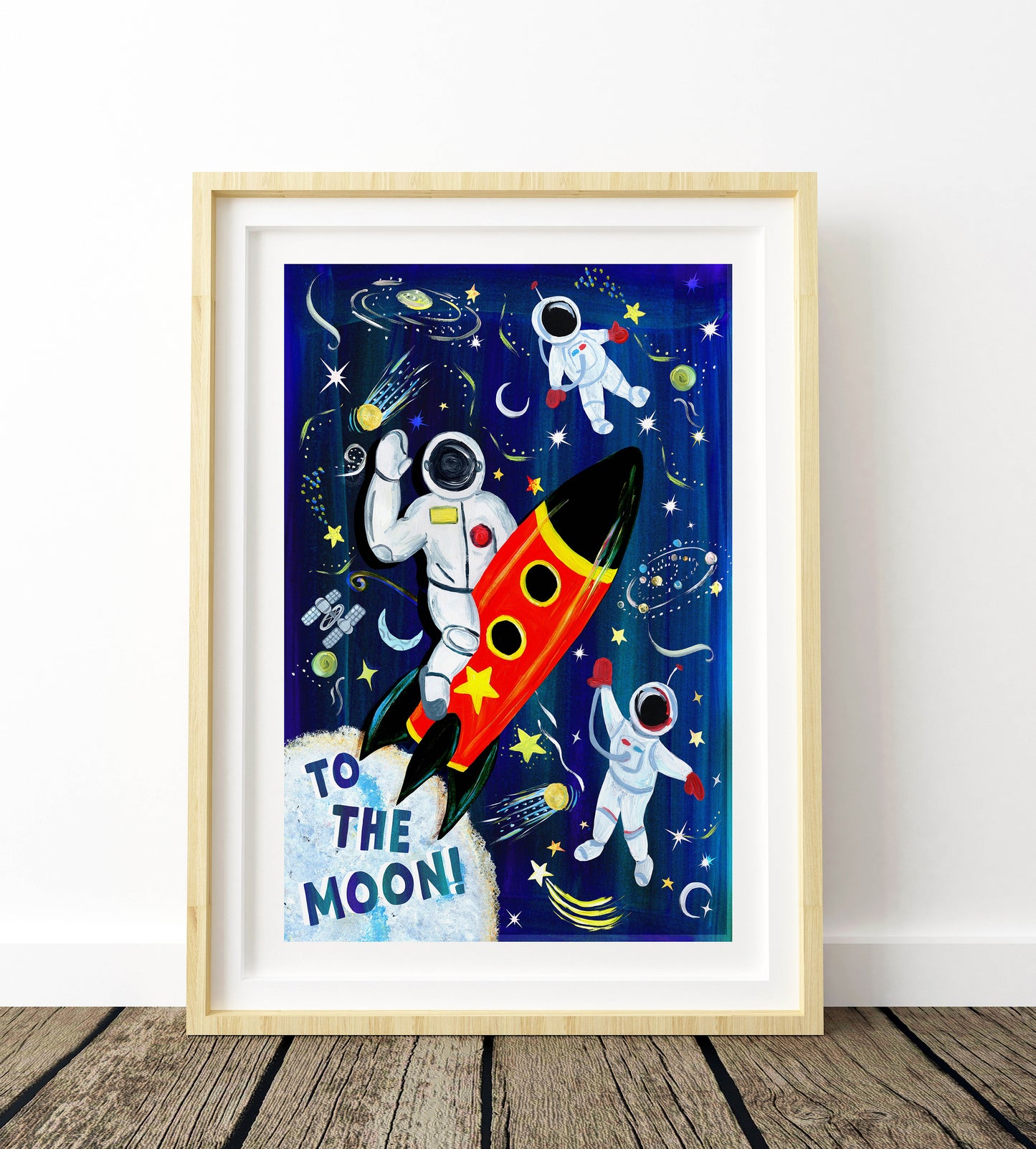 Framed artwork of an astronaut and rocket ship with 'To the Moon!' text against a space-themed background.