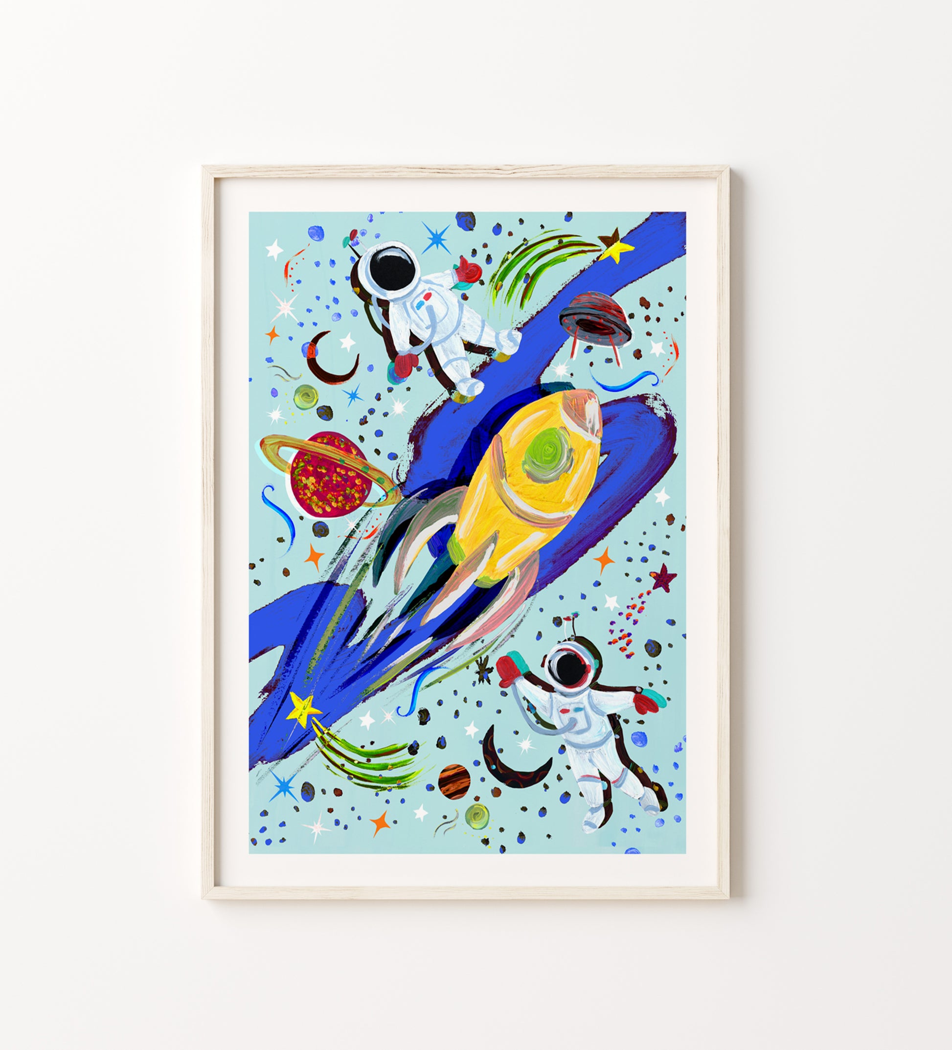 Framed artwork of a colorful space-themed illustration with astronauts and rockets on a light blue background.