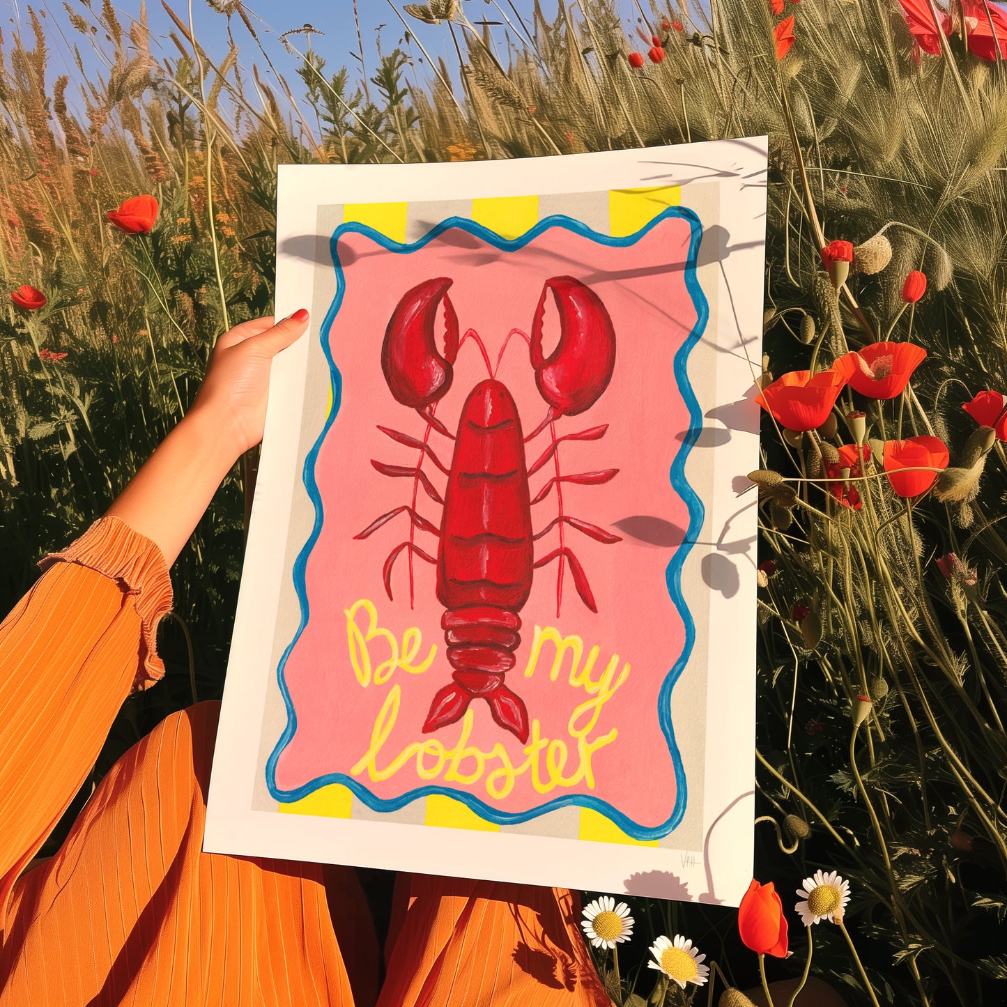 Person holding a print with a lobster illustration and 'Be my lobster' text in a field of flowers.