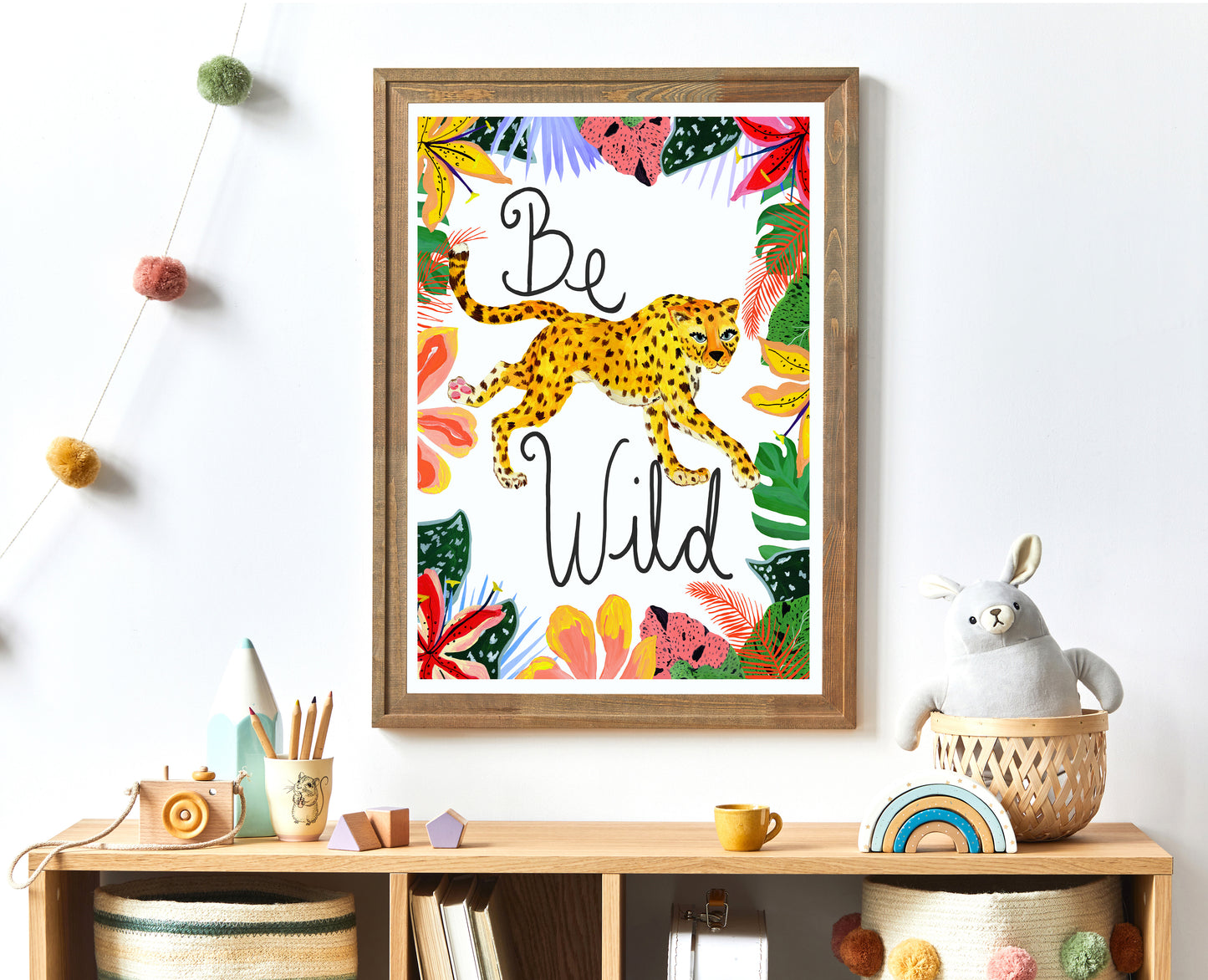 Framed artwork with a leopard and 'Be Wild' text on a shelf with decorative items.