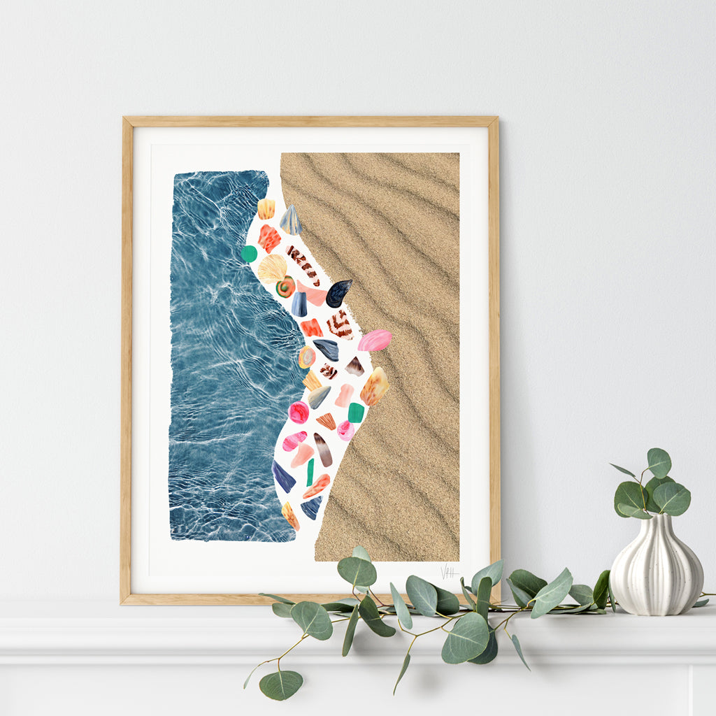 Framed artwork with a beach design featuring sand and water, displayed on a wall.