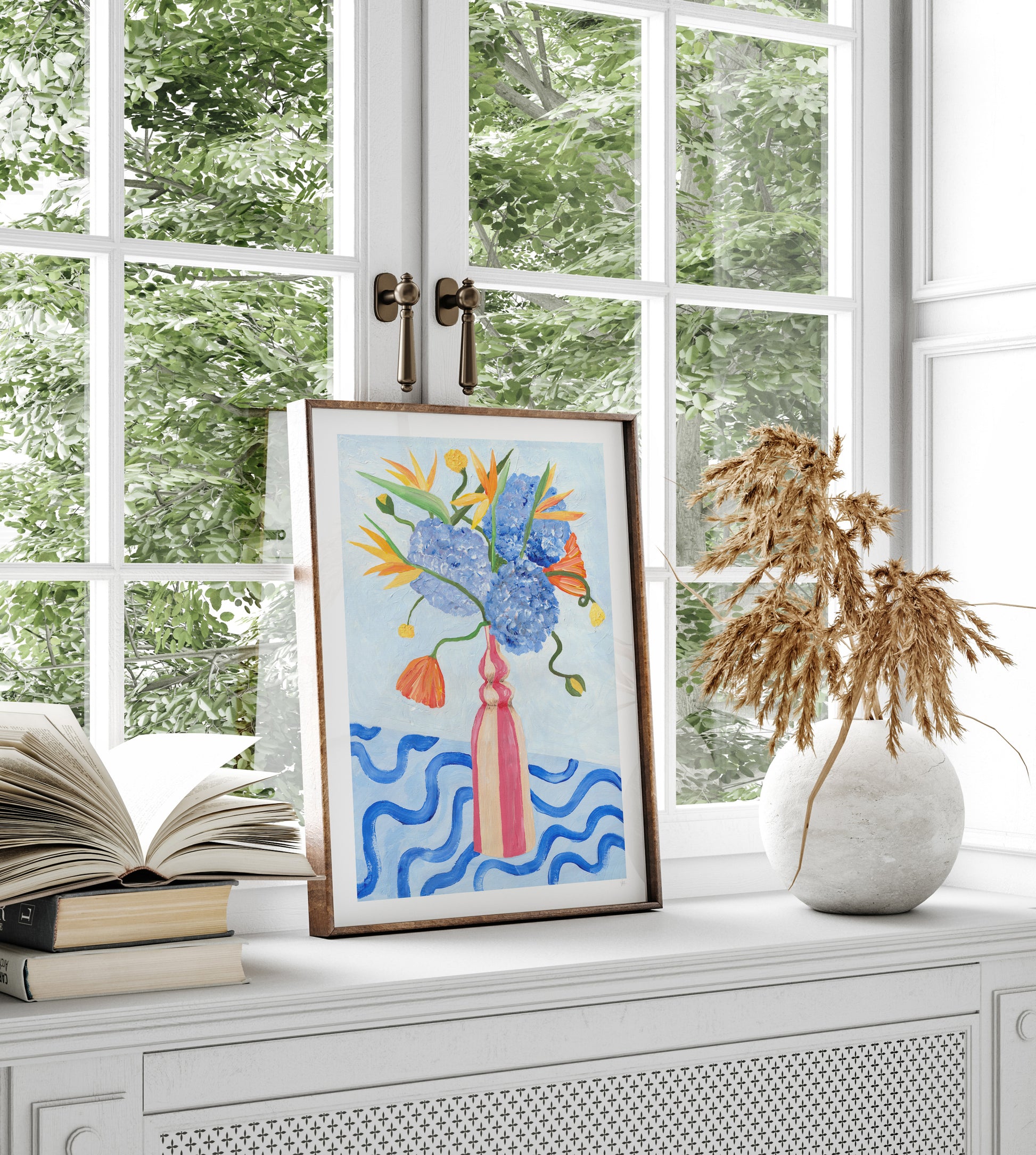 Framed artwork with floral design on a windowsill with books and a vase.