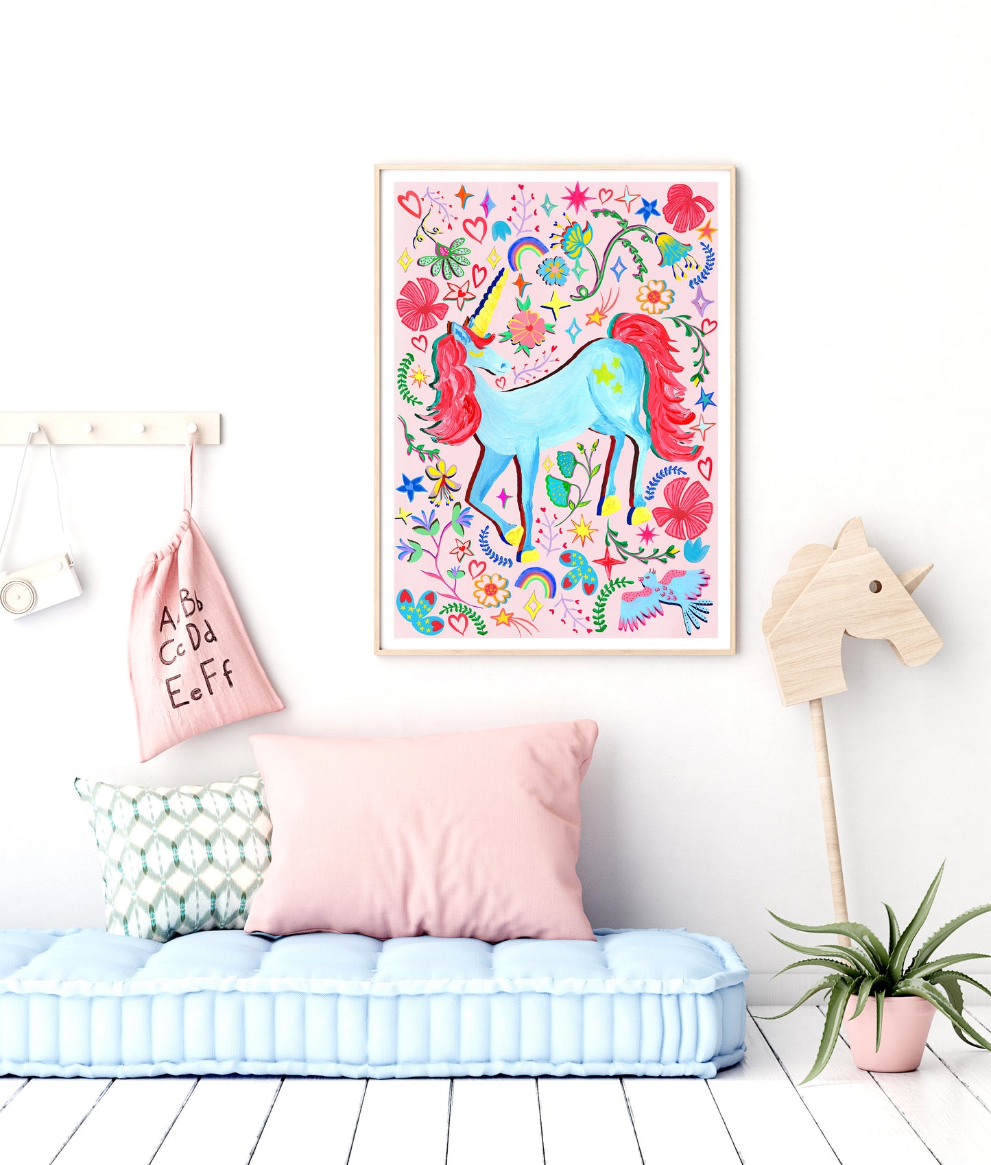 A kids room with a light pink background unicorn painting on a white wall
