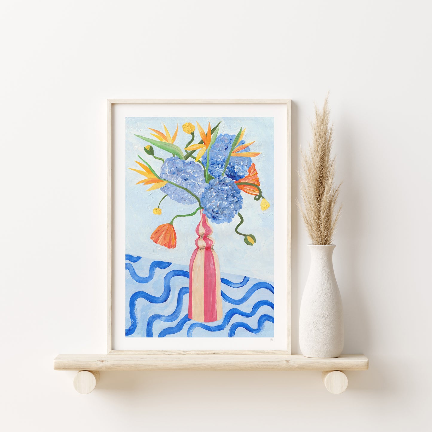 Framed floral artwork on a white wall with a vase of dried plants.