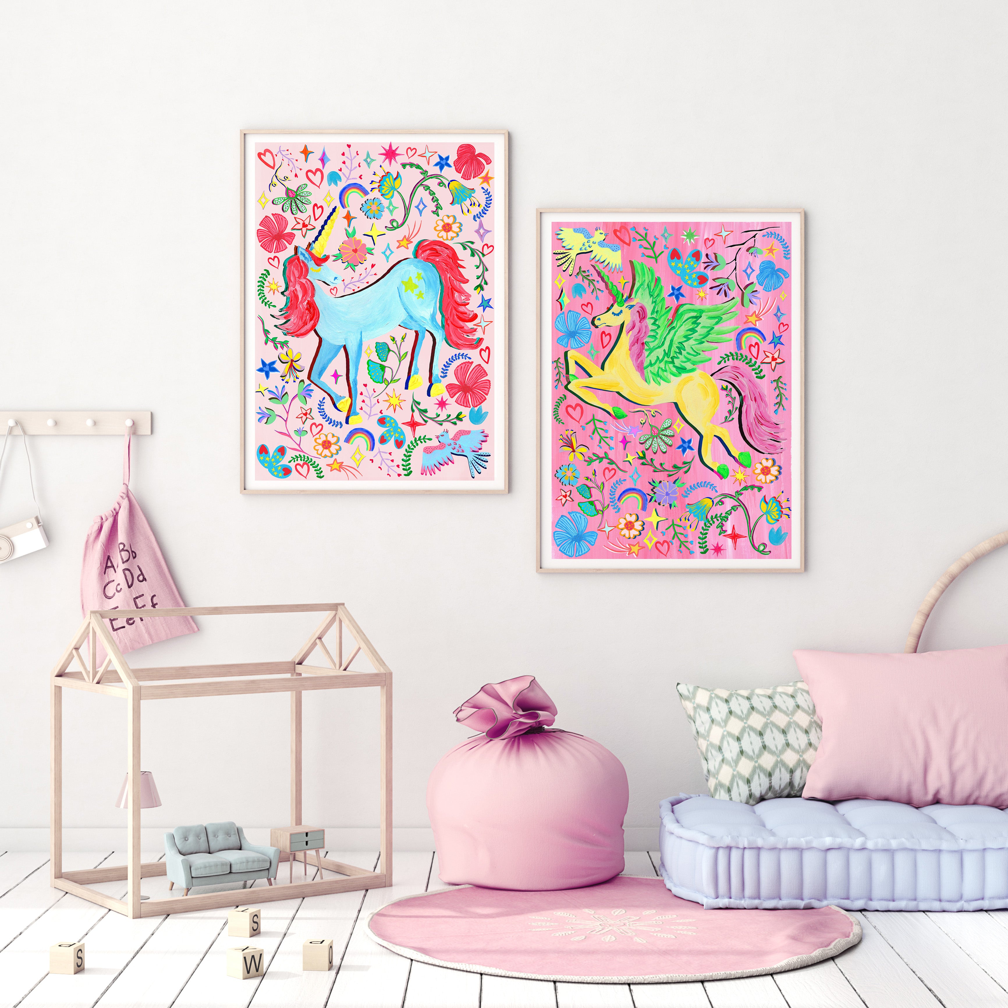 A childs white room with pink and blue floor cushions and colourful hand painted unicorn art prints on a white wall.
