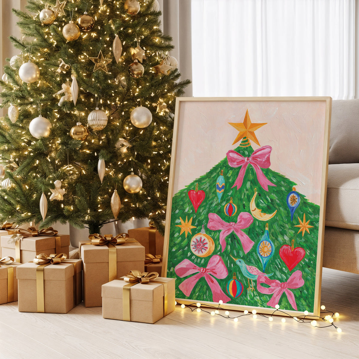 A framed colorful painting of a Christmas tree with pink bows and ornaments, leaning against a sofa beside a decorated Christmas tree and wrapped gift boxes on a light wood floor.