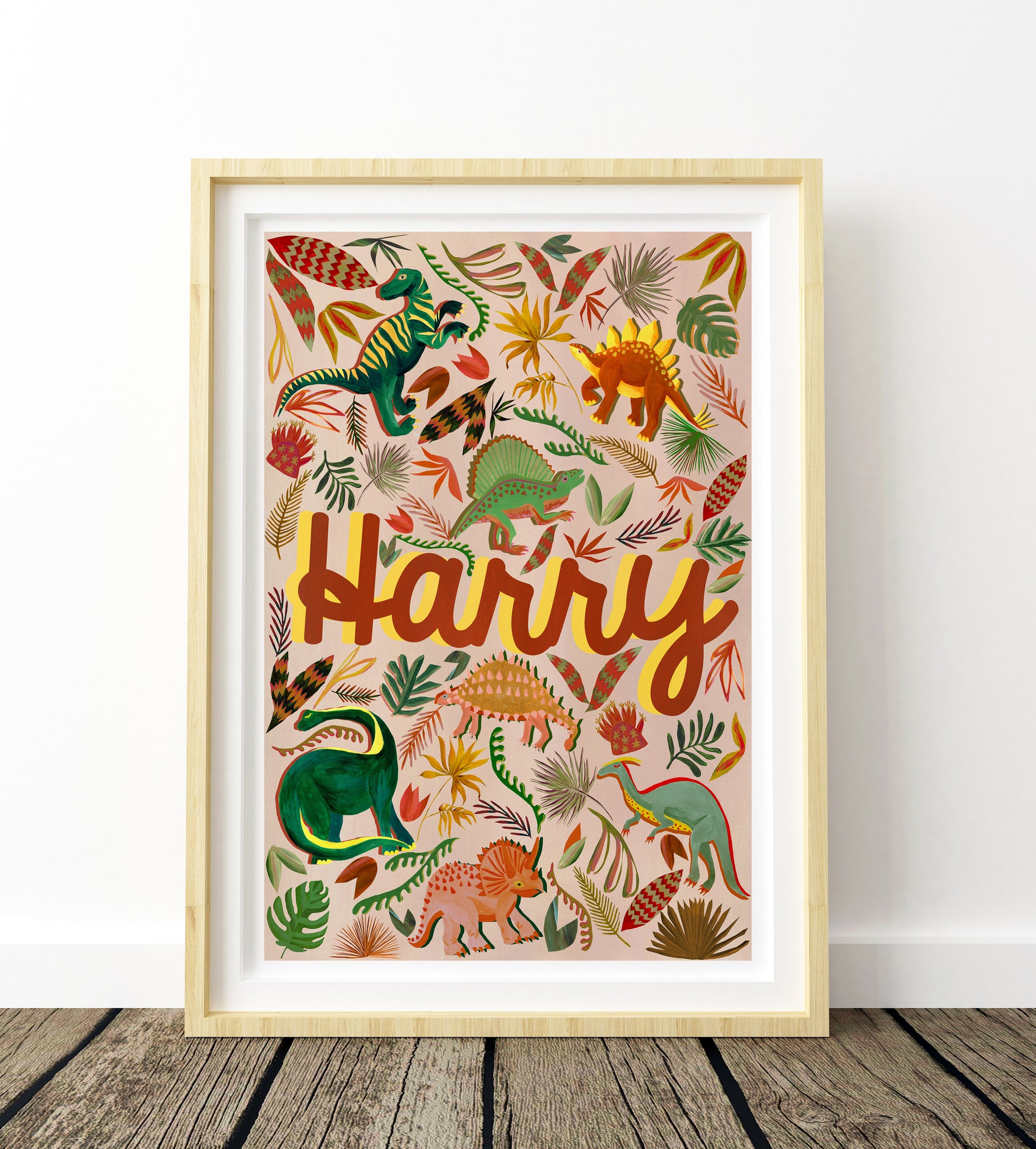 Framed artwork with colorful dinosaurs and the name 'Harry' on a white wall.
