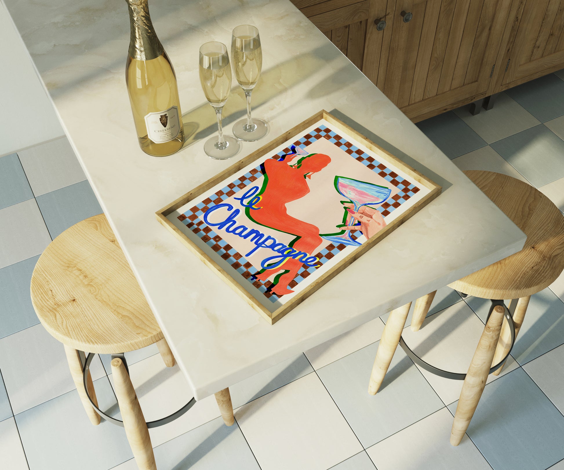 Table with a colorful tray, champagne bottle, and glasses in a kitchen setting.