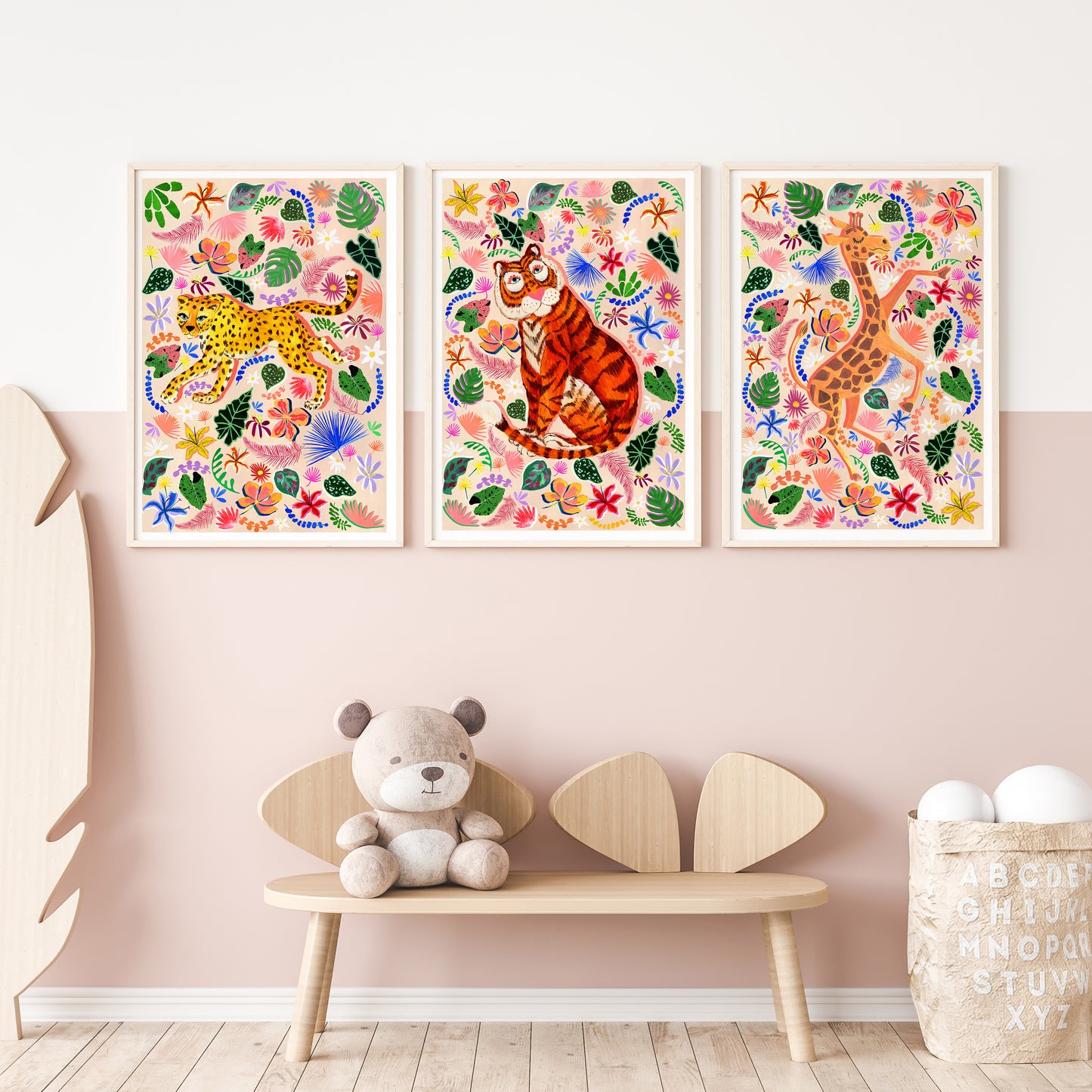 Three colorful animal prints on a wall above a wooden bench with a teddy bear.