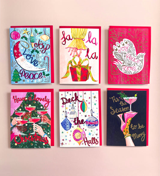Six colorful Christmas greeting cards arranged in a 2x3 grid on a light beige background. The cards feature festive illustrations and holiday greetings including ' Merry Love Peace', 'Jolly La La La', 'Joy to the World', 'Have a lovely Christmas', 'Deck the Halls', and 'It's the Season to be Merry'.