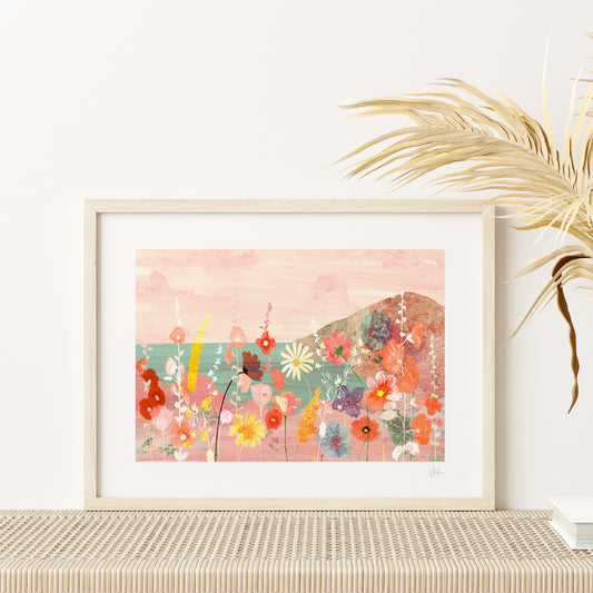 Framed floral artwork on a table with a plant in the background