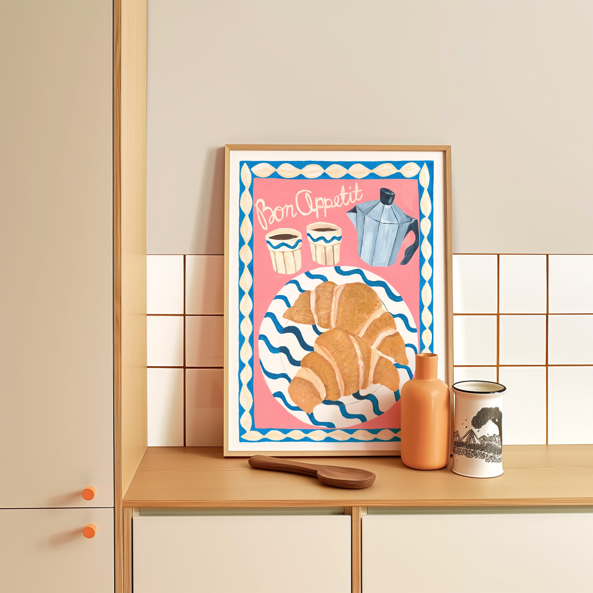 Framed artwork with a croissant and coffee pot design on a kitchen counter.