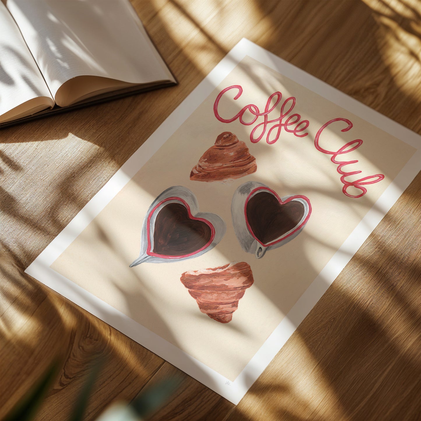 Poster with 'Coffee Club' design on a wooden surface with an open book.