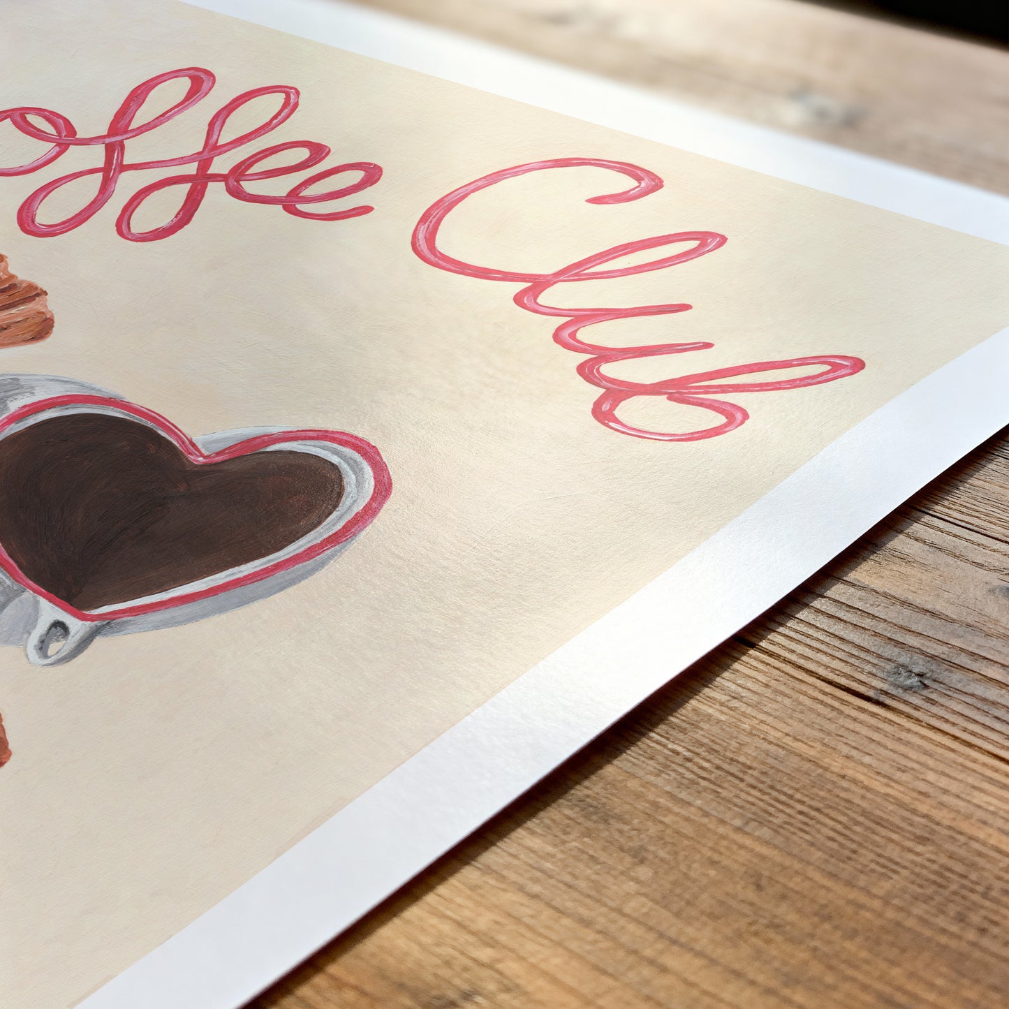 Poster with 'Coffee Club' text and heart-shaped coffee cup on a wooden surface