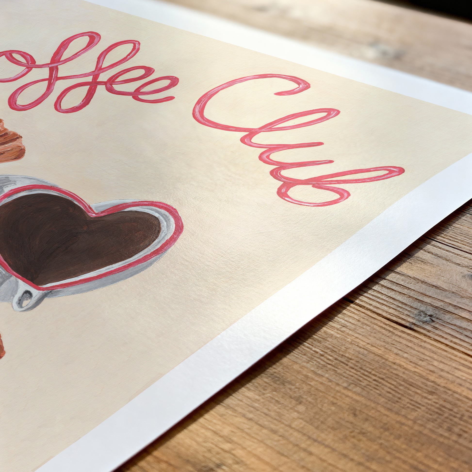 Poster with 'Coffee Club' text and heart-shaped coffee cup on a wooden surface