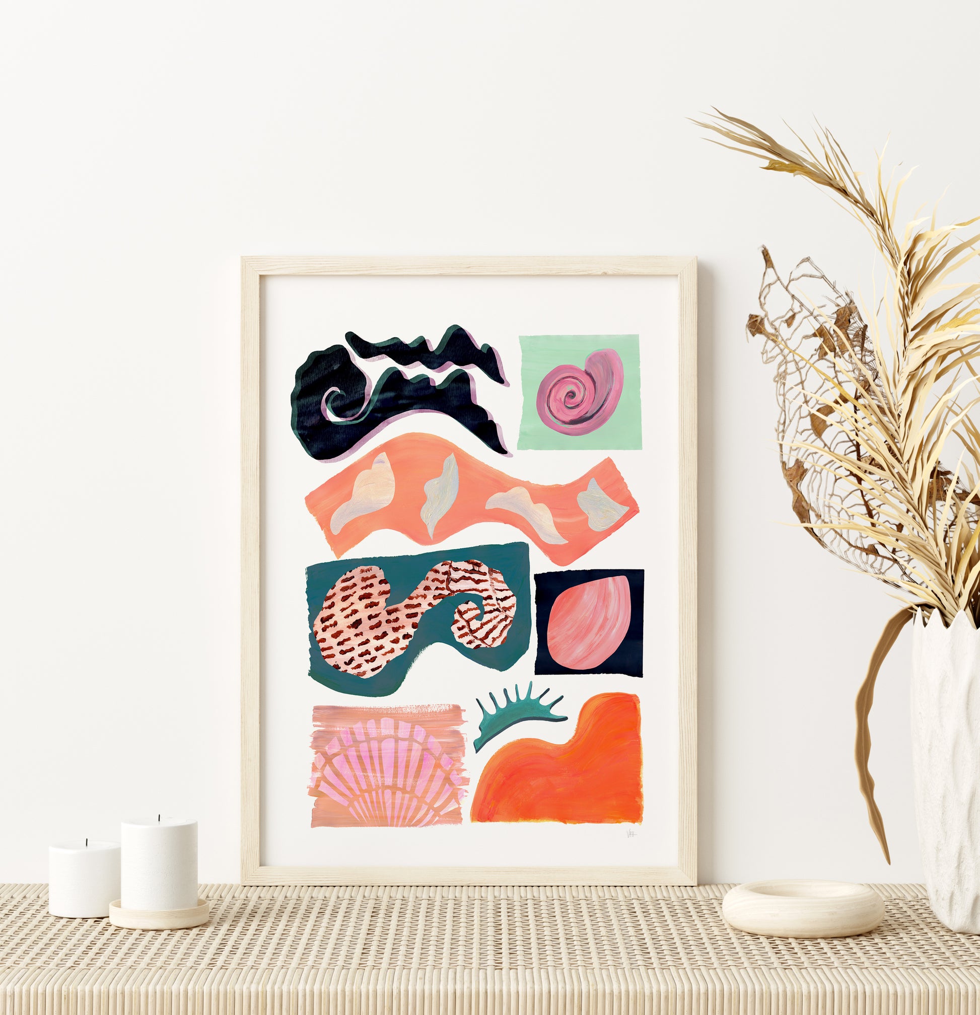 Framed abstract artwork with colorful shapes on a wall above a table.