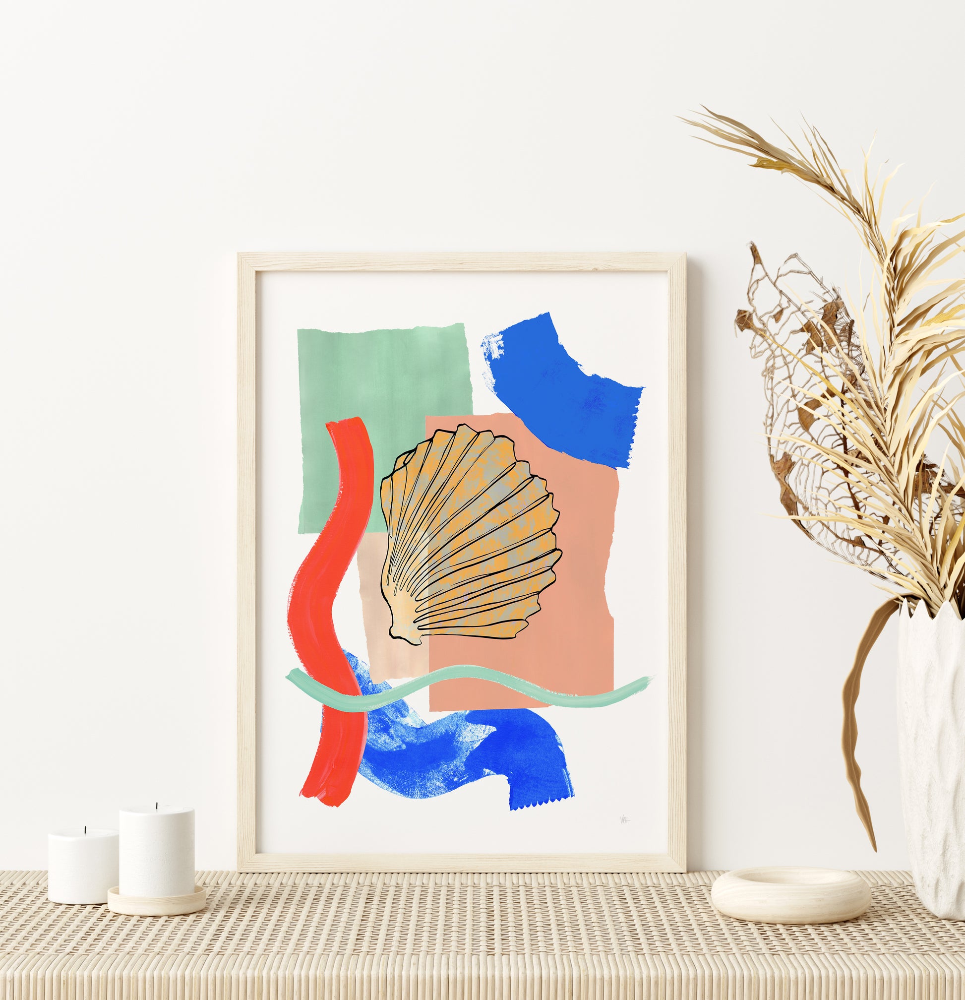 Framed abstract art print with colorful shapes on a wall above a table.