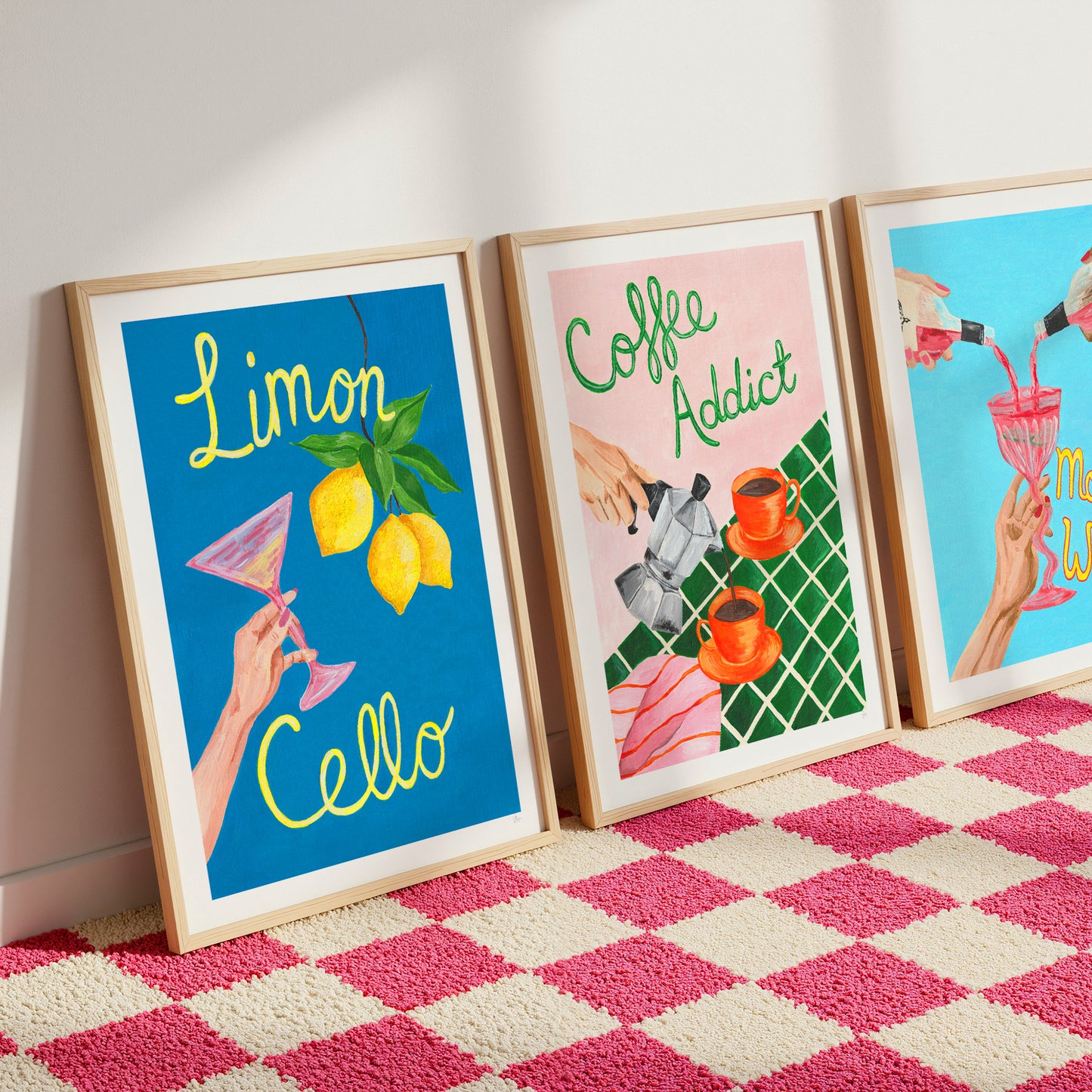 Three framed artworks on a pink and white checkered rug.