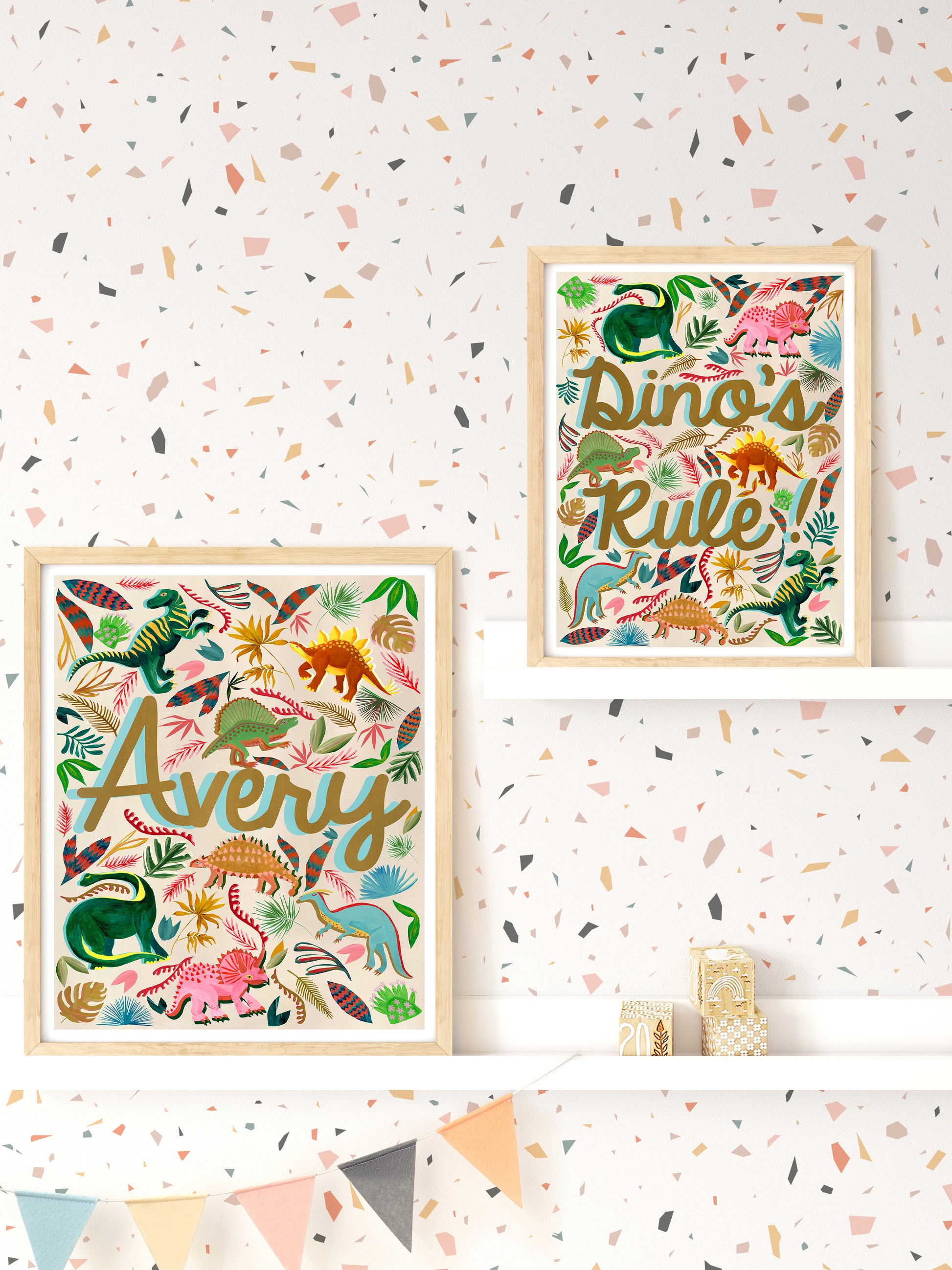 Two framed dinosaur-themed prints on a wall with a terrazzo pattern.