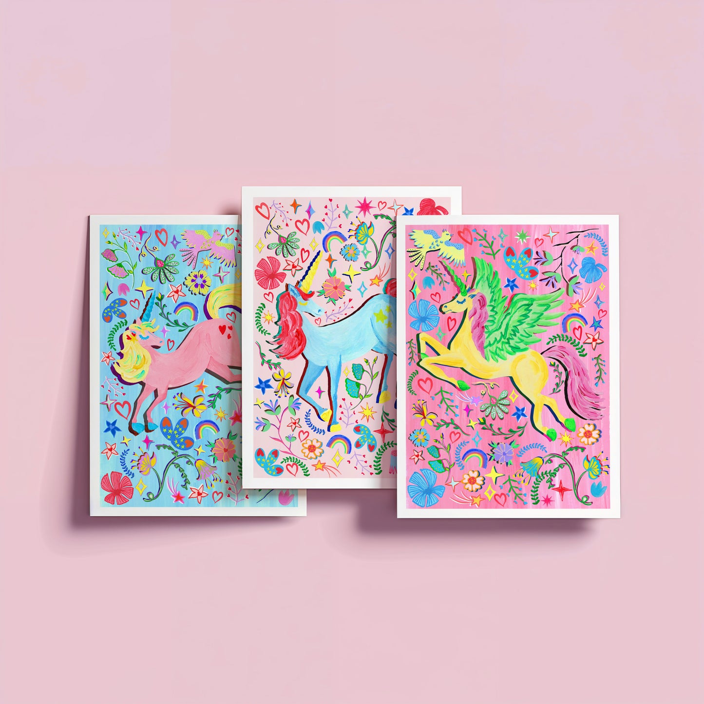 Three colorful greeting cards with unicorns on a pink background