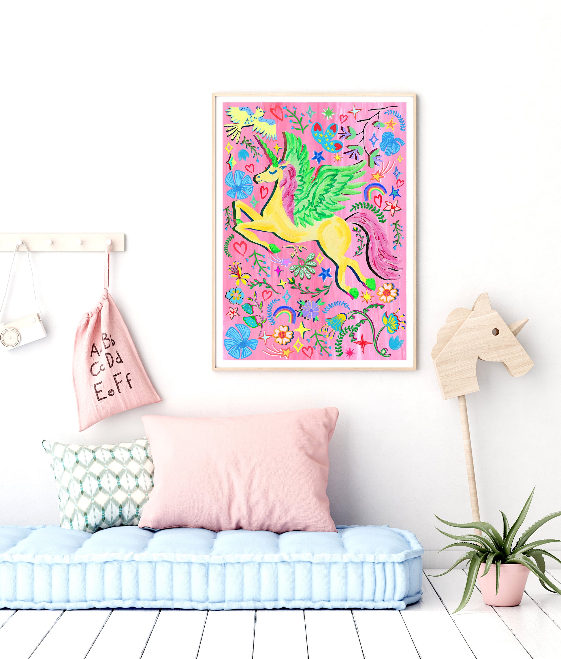 Colorful unicorn artwork on a wall in a child's room with a pink pillow and plant.