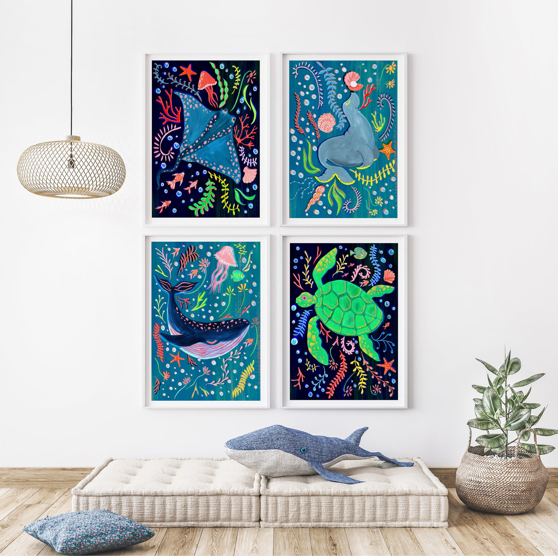 Four colorful framed artworks of marine life on a wall above a bench with a shark pillow.