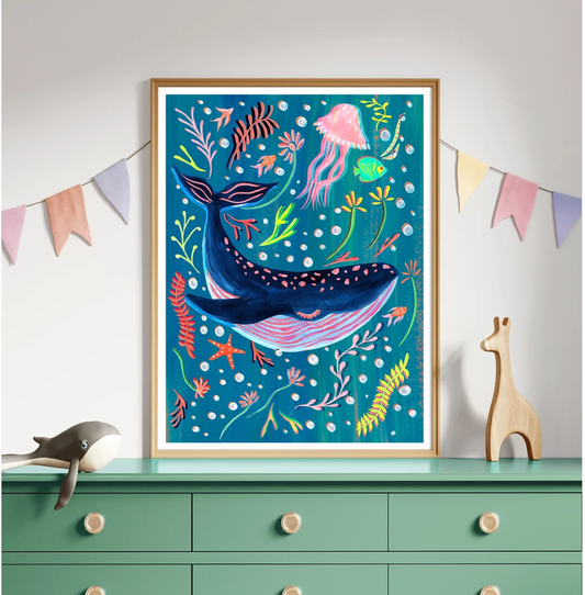 Colorful whale illustration in a wooden frame on a dresser with decorative flags.