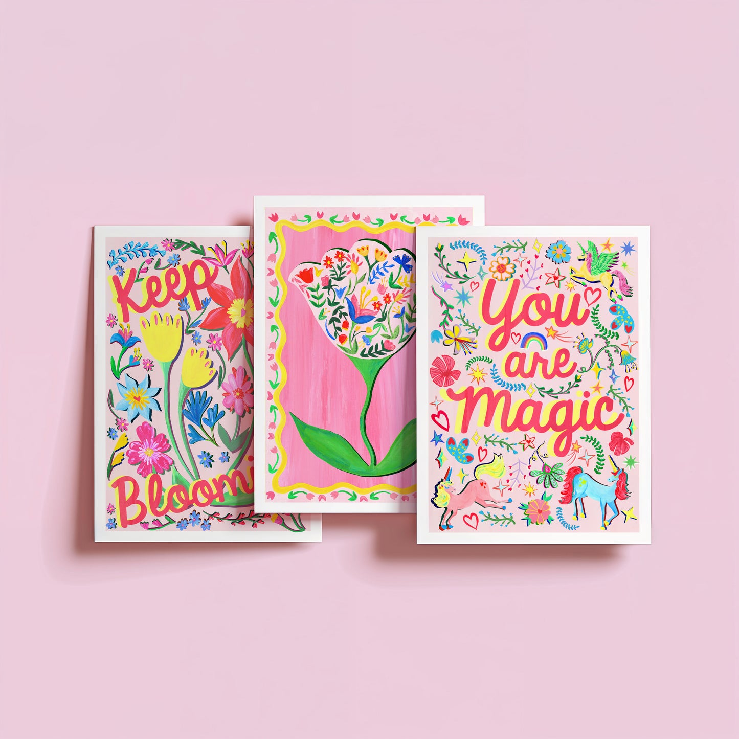 Three colorful greeting cards with floral and motivational text on a pink background