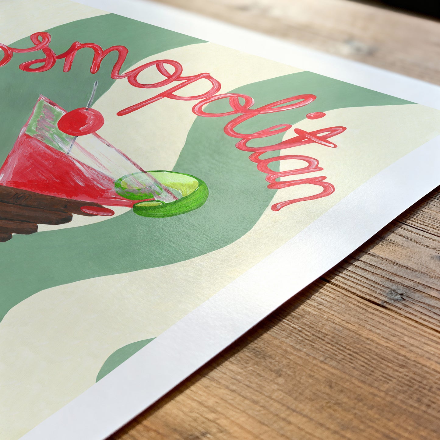 Poster of a cocktail with 'Cosmopolitan' text on a wooden surface