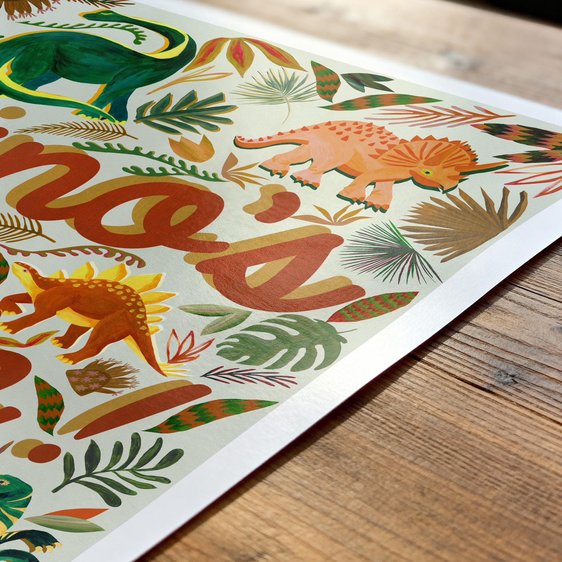 Colorful dinosaur illustration on a paper with 'hello' text, placed on a wooden surface.