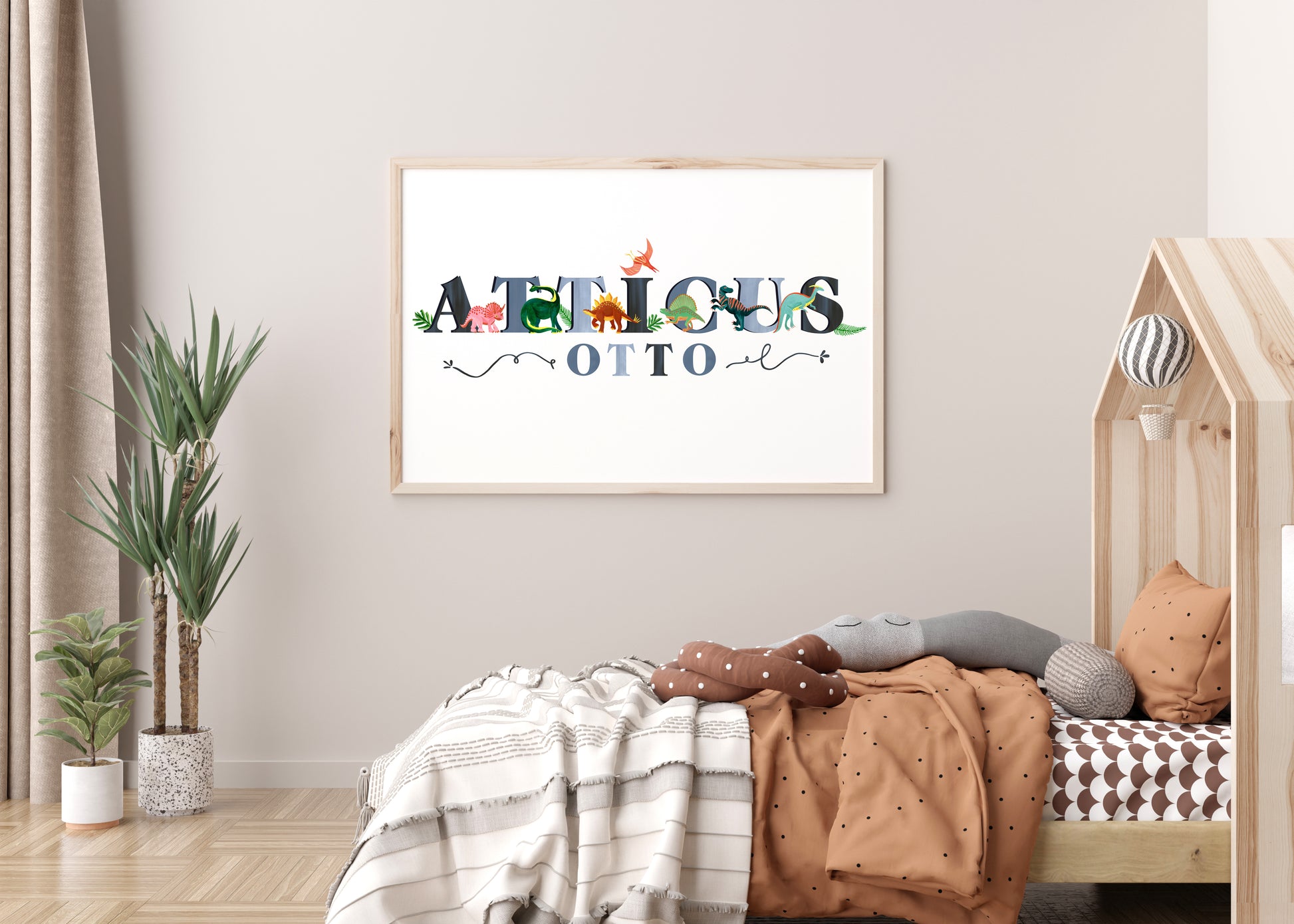 Children's room with a framed dinosaur illustrated name artwork on the wall, bed with pillows, and plants.