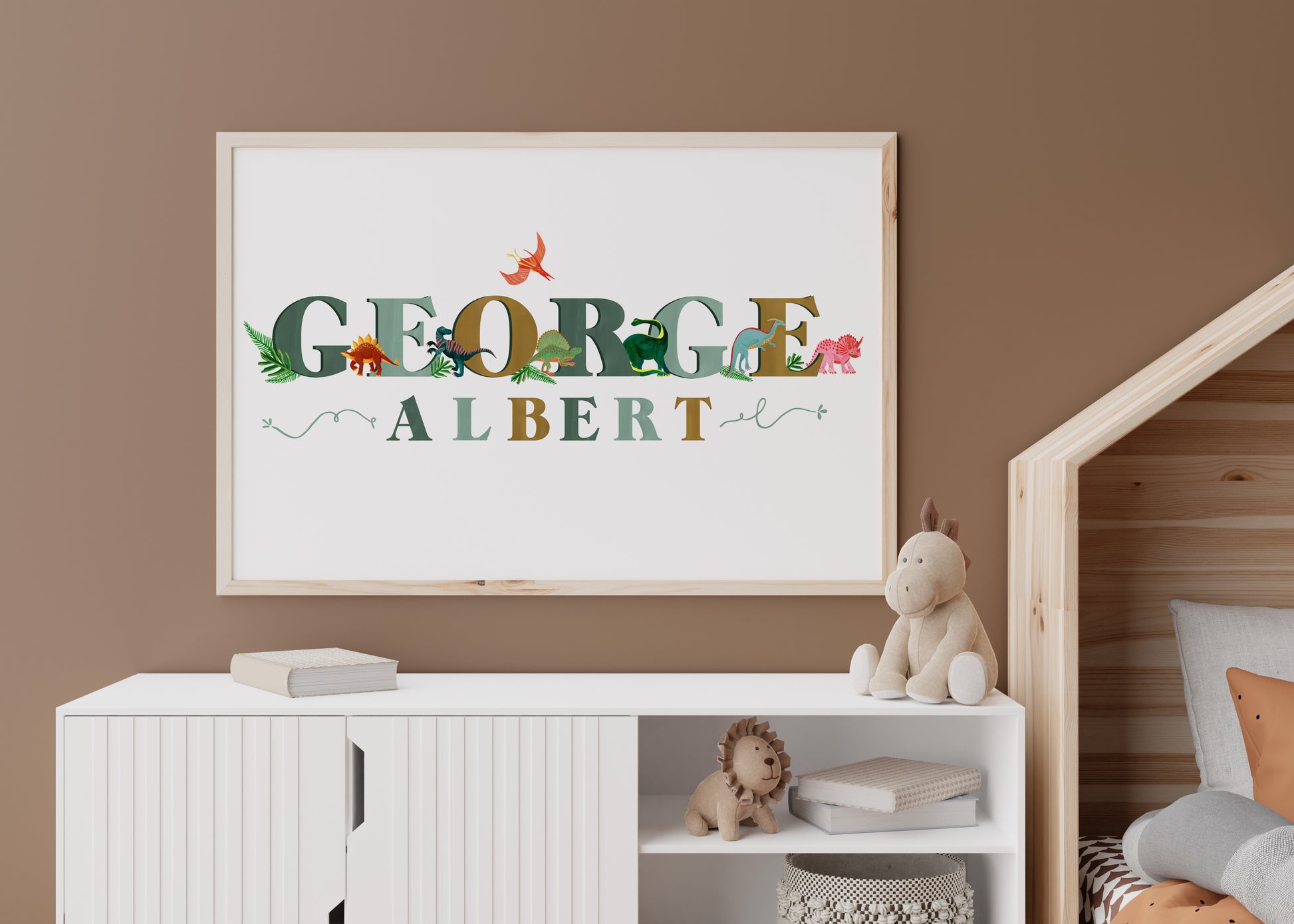 Framed children's name art with dinosaurs on a wall in a nursery.
