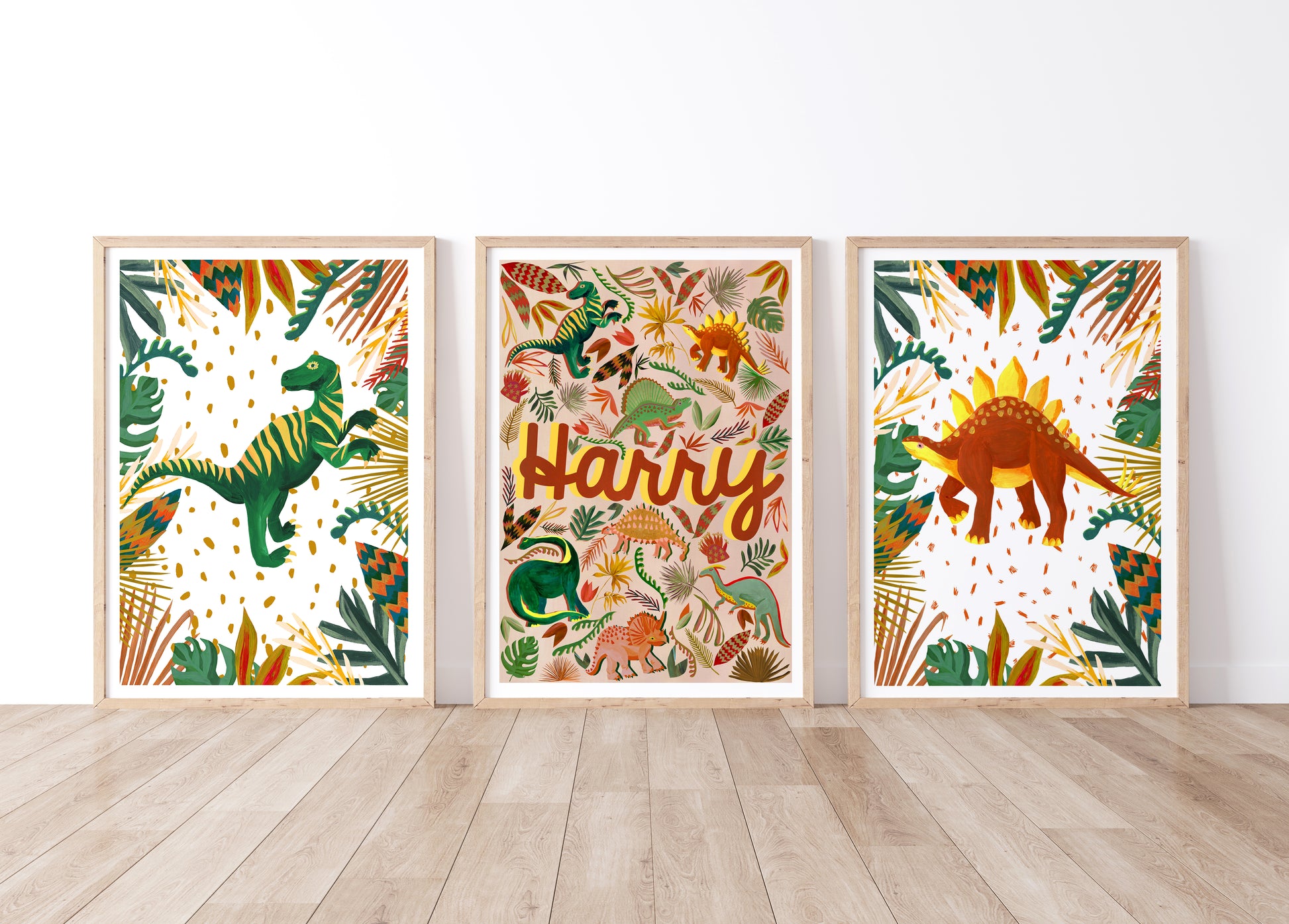 Three framed dinosaur-themed prints with a name on a white wall.