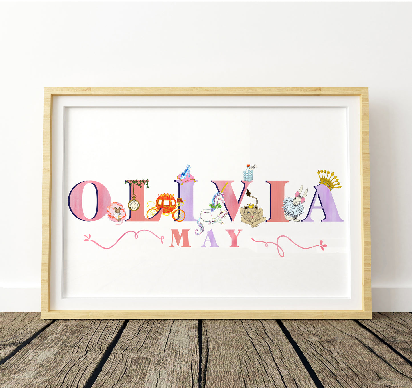 Framed artwork with 'OLIVIA MAY' in colorful letters with fairytale illustrations decorating the letters on a white background