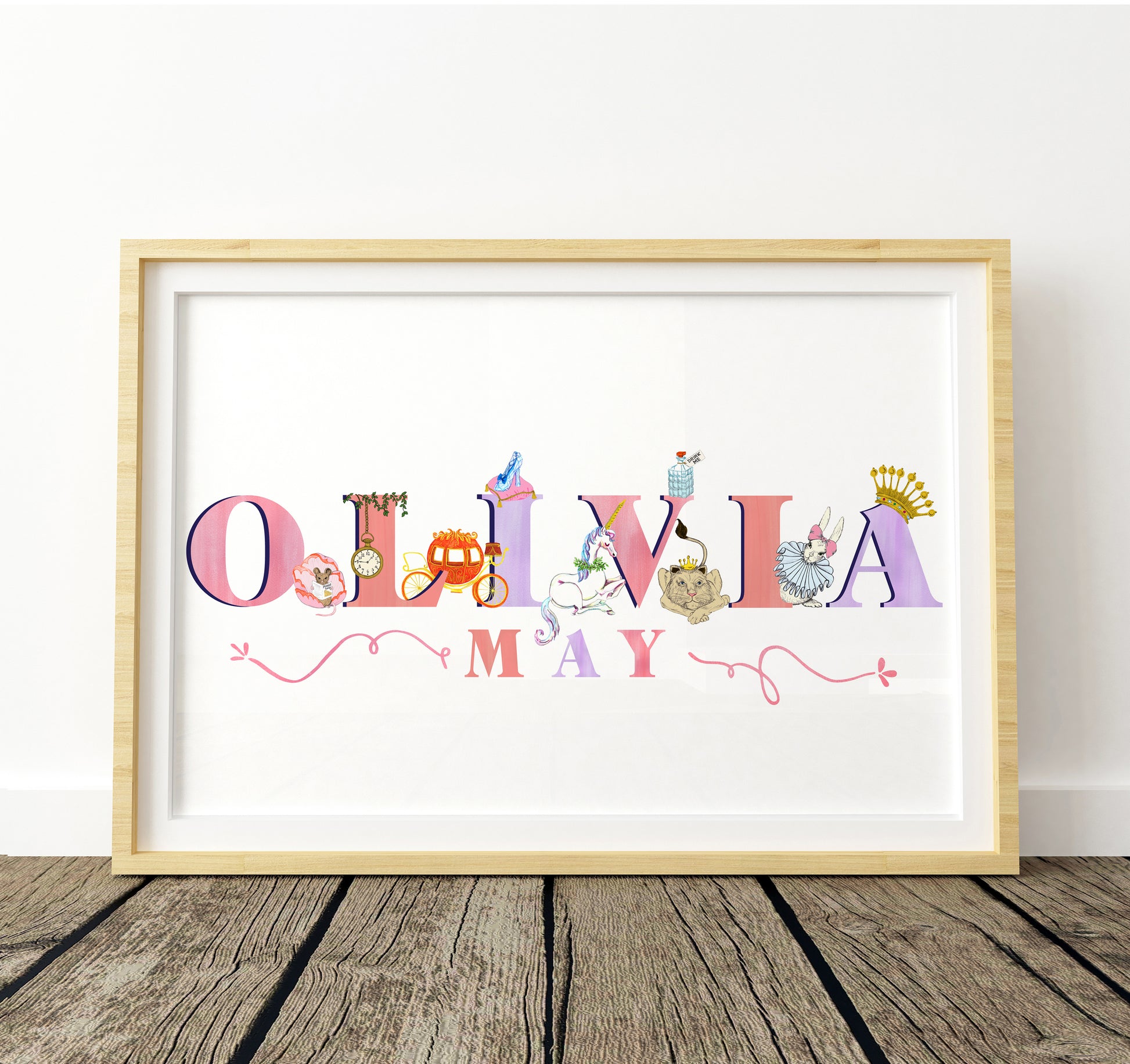Framed artwork with 'OLIVIA MAY' in colorful letters with fairytale illustrations decorating the letters on a white background