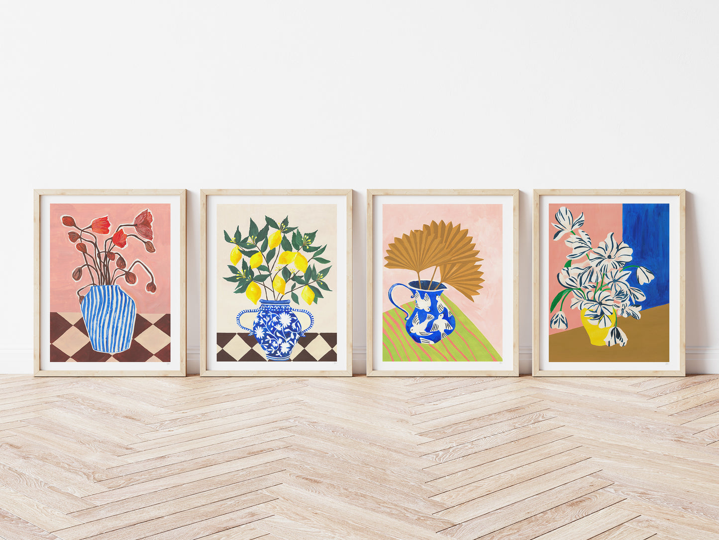 Four framed artworks with floral and vase designs on a wooden floor.