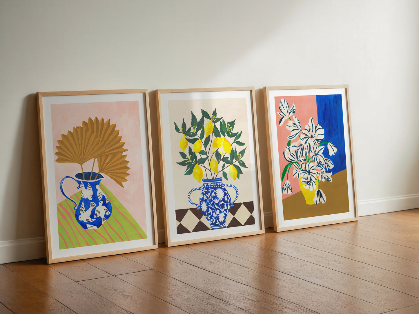 Three framed artworks on a wooden floor against a white wall