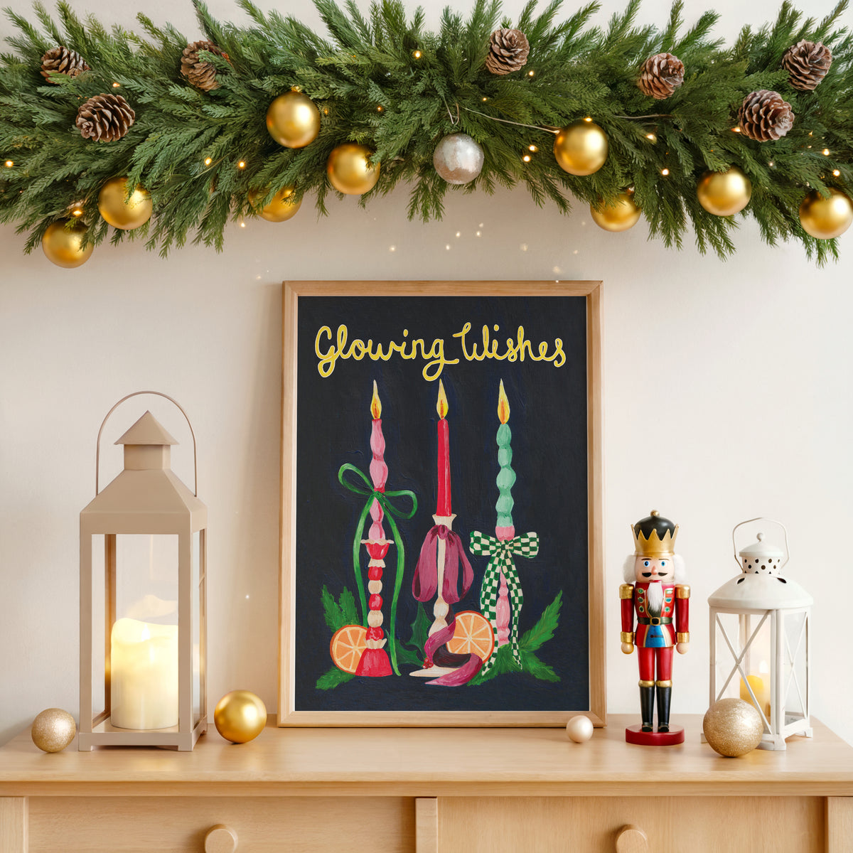 A framed Christmas art print with the text 'Glowing Wishes' hangs on a wall above a wooden console table. The print features colorful candles and ornaments on a dark background.