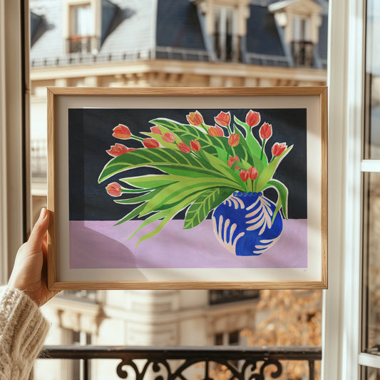 Framed artwork of a blue vase with flowers held in front of a window with a cityscape view.