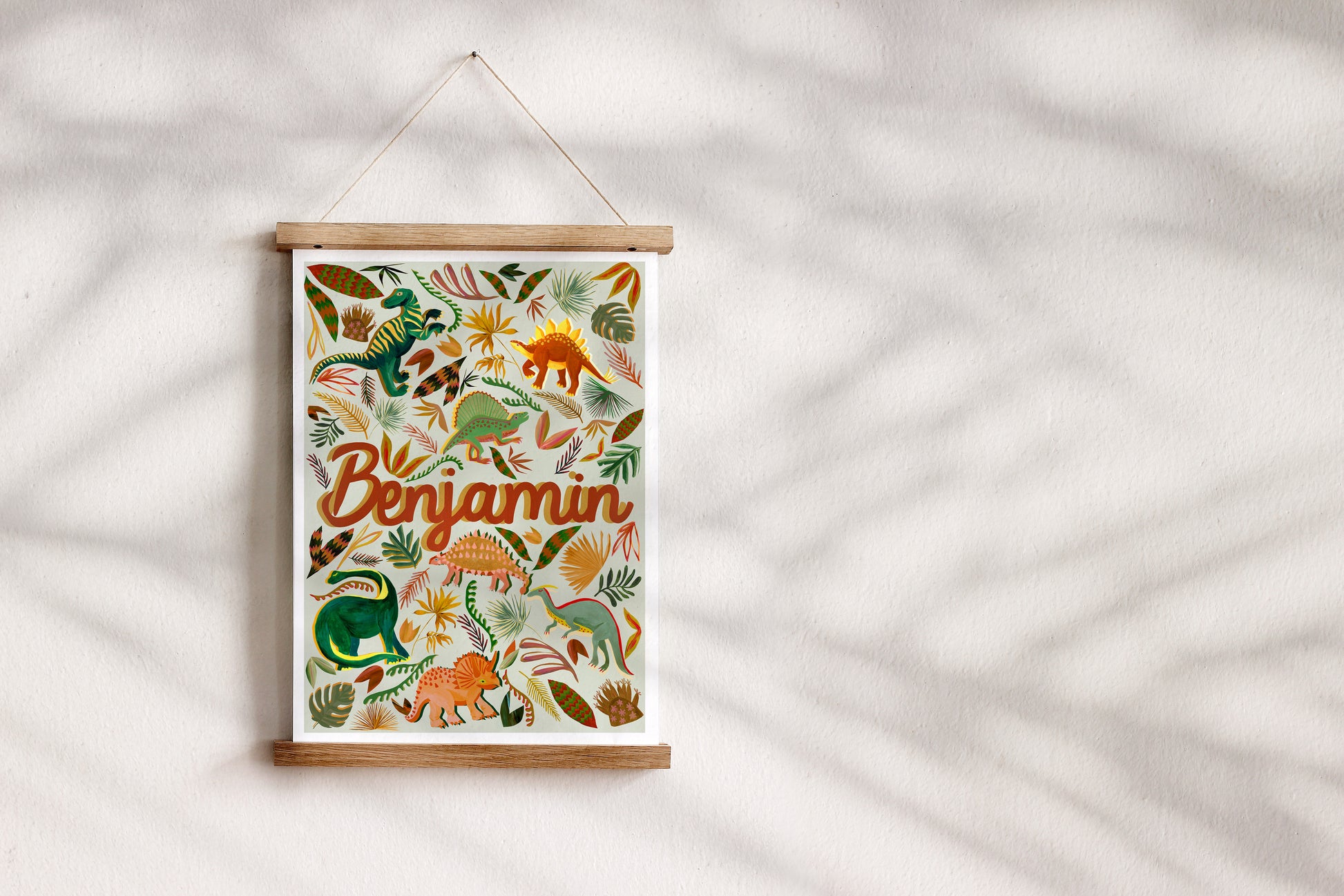 Decorative wall hanging with dinosaur illustrations and the name 'Benjamin' on a white background