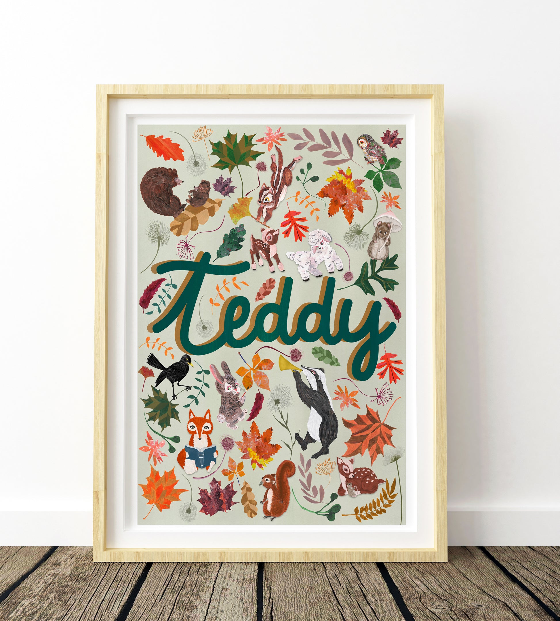 Framed artwork with 'Teddy' and various animals and leaves on a white wall.