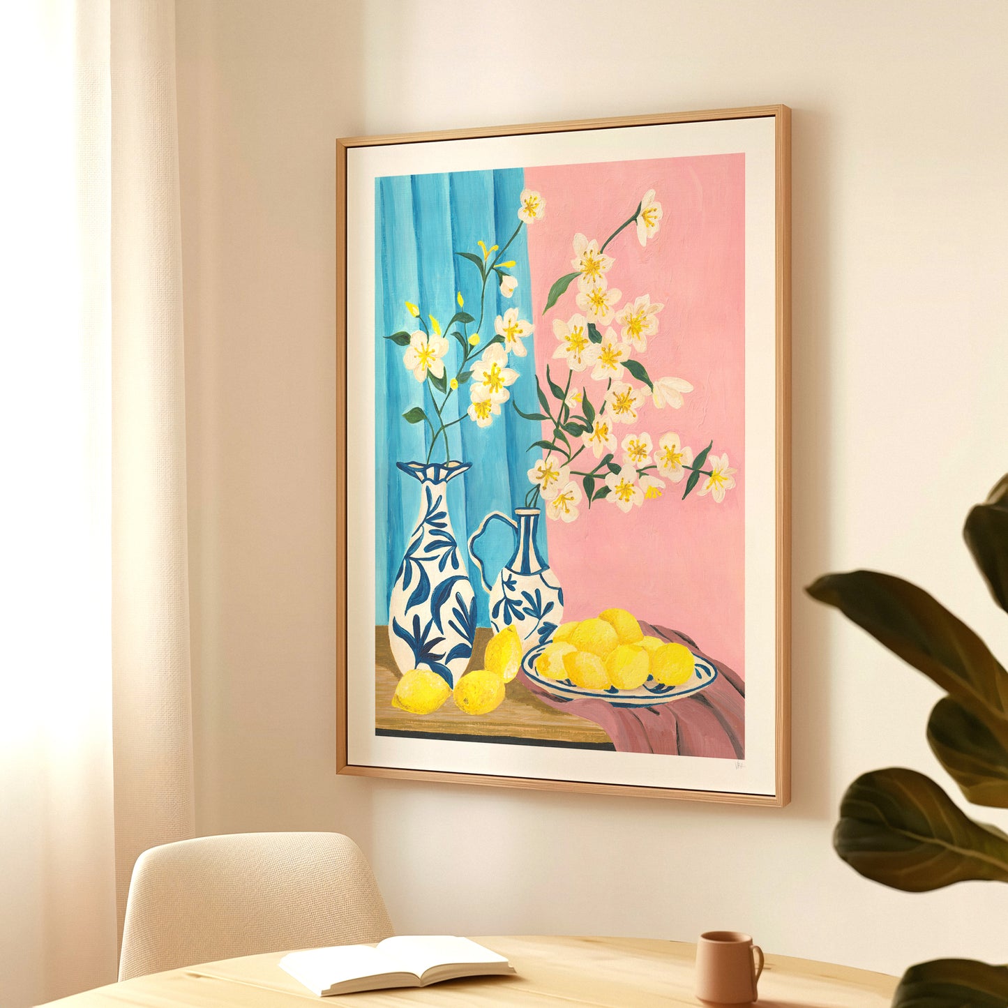 Framed artwork with floral and decorative elements on a wall above a table.