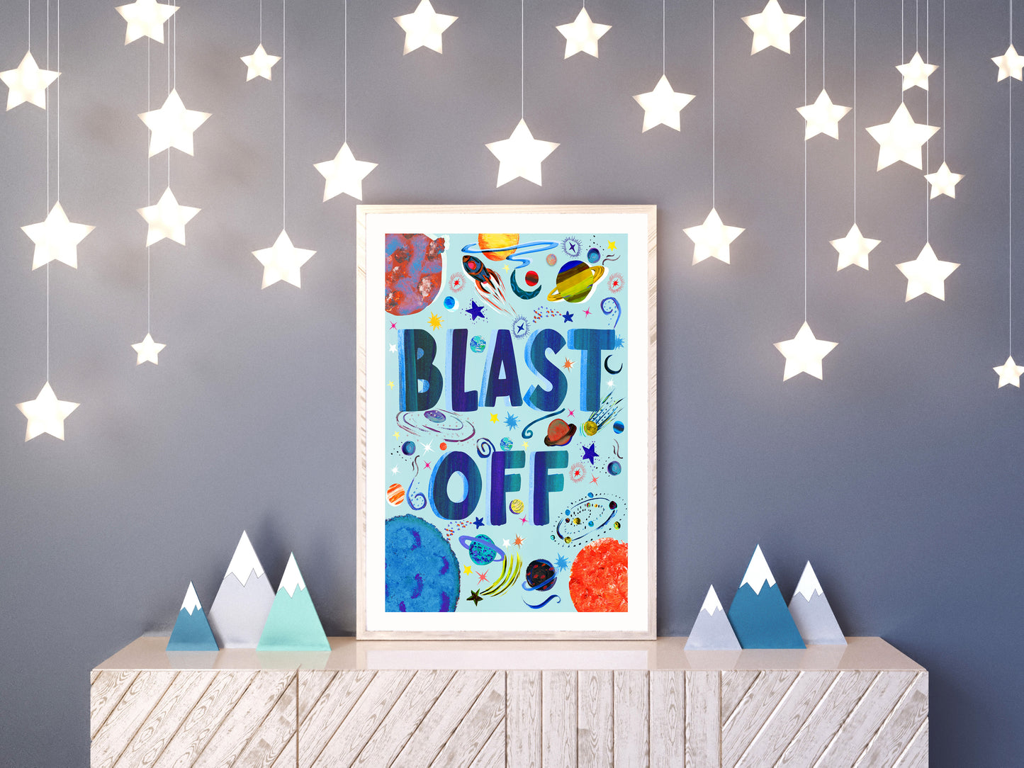 Children's wall art with 'BLAST OFF' text and space-themed design, hanging above a shelf with star decorations.