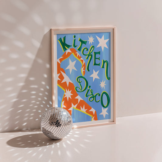 Framed artwork with 'Kitchen Disco' text and a disco ball on a light surface.