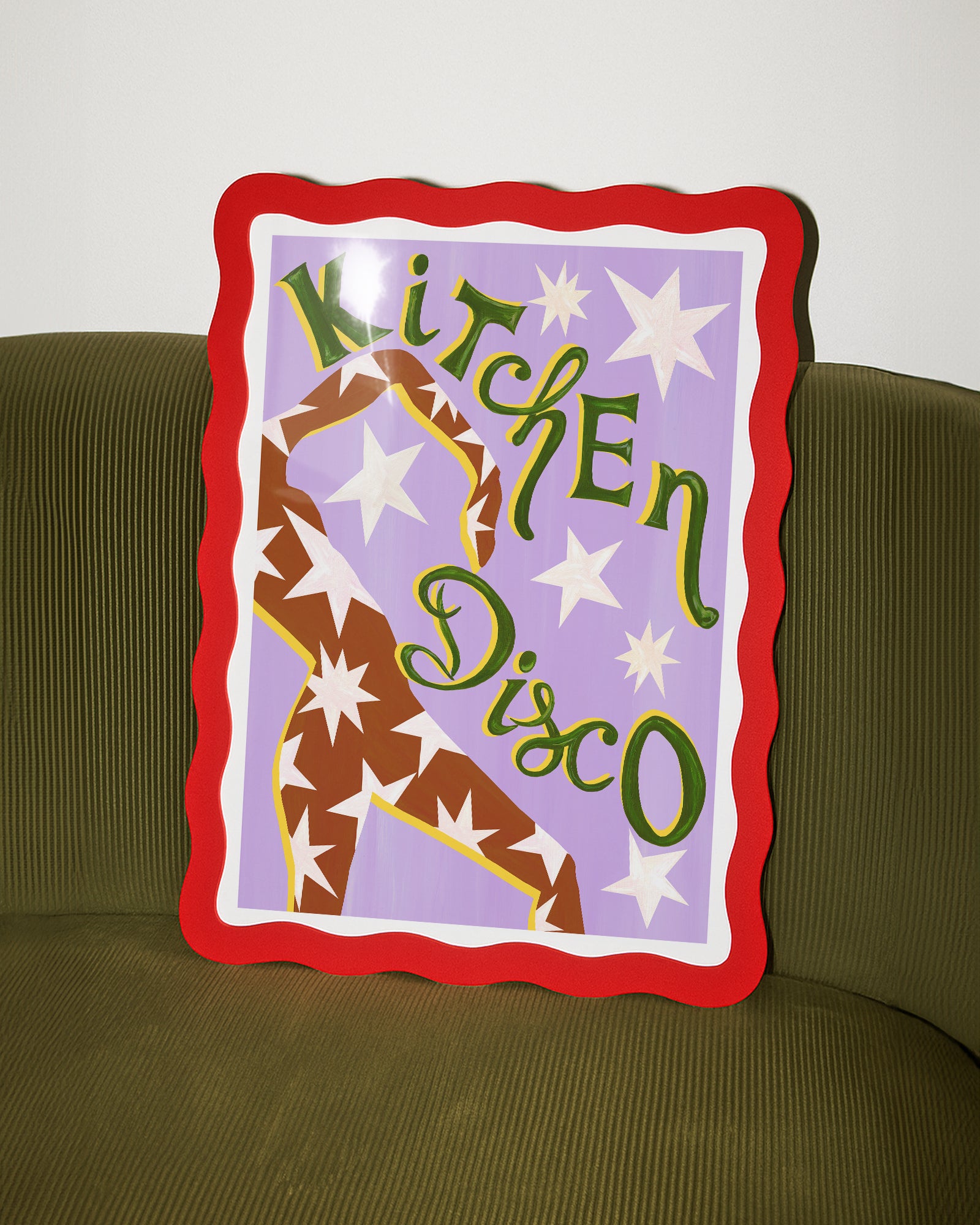 Decorative pillow with 'Kitchen Disco' text and star design on a green couch.